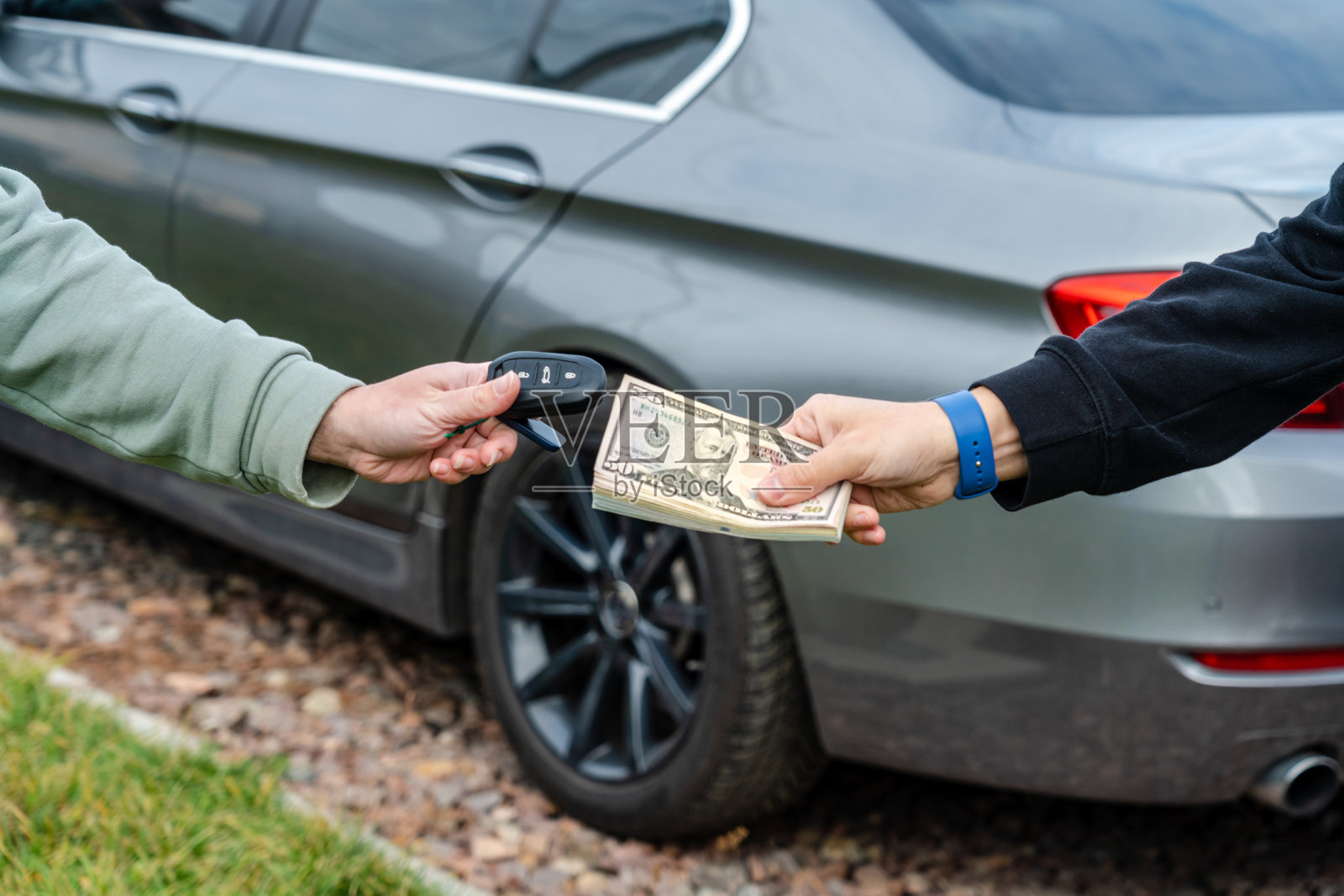 交易购买或租赁汽车的概念。一只手拿车钥匙，另一只手给钱。照片摄影图片