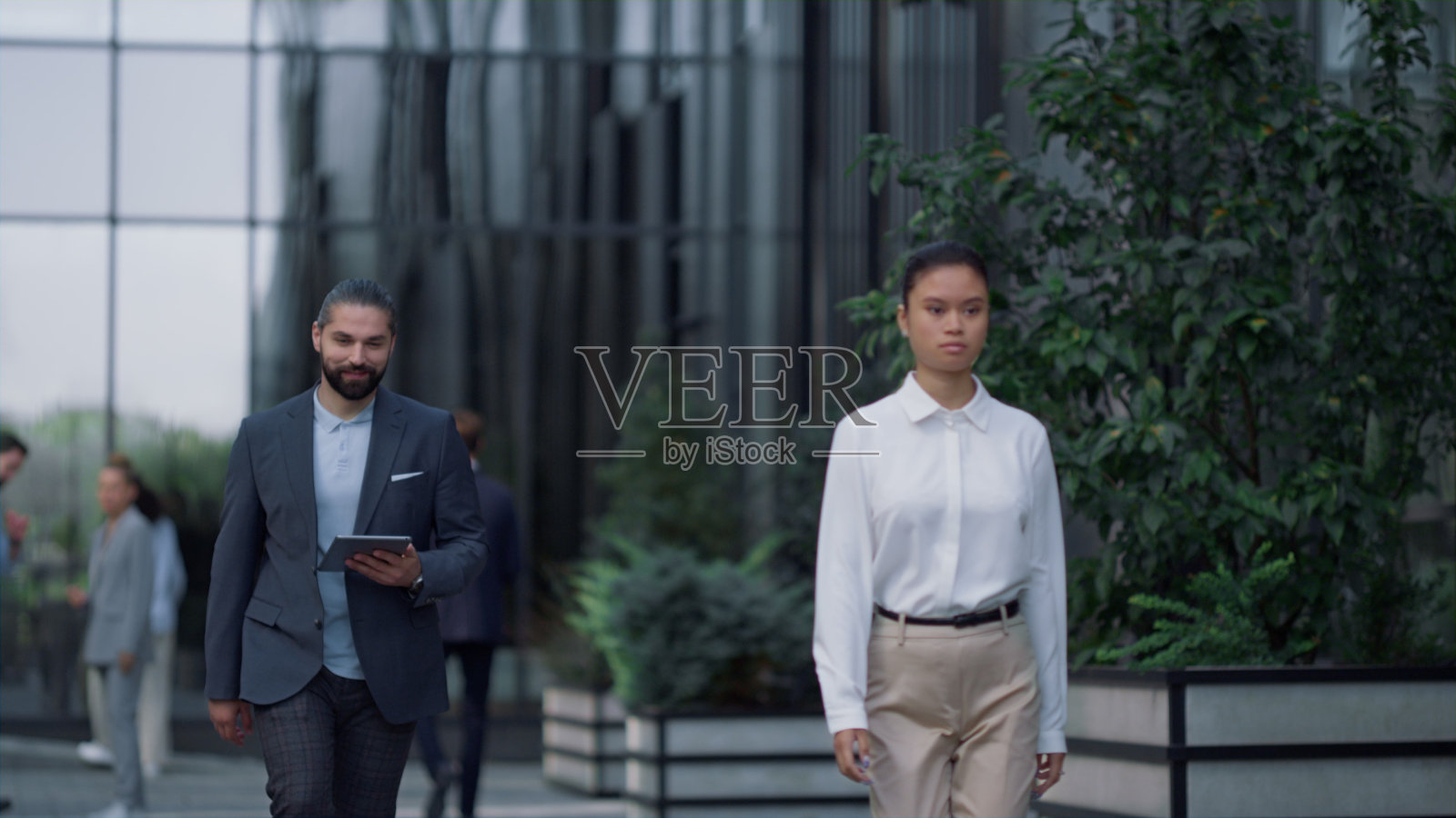 微笑的商人带着平板电脑走在市中心的商业中心。照片摄影图片