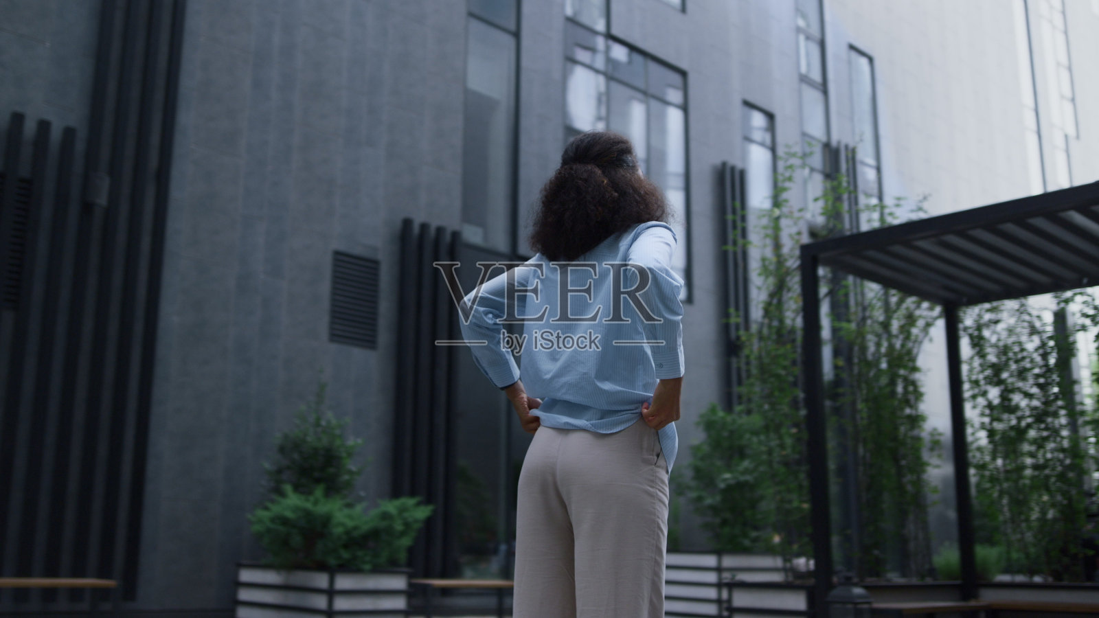 微笑的女人站在现代办公大楼看着相机。骄傲的赢家照片摄影图片