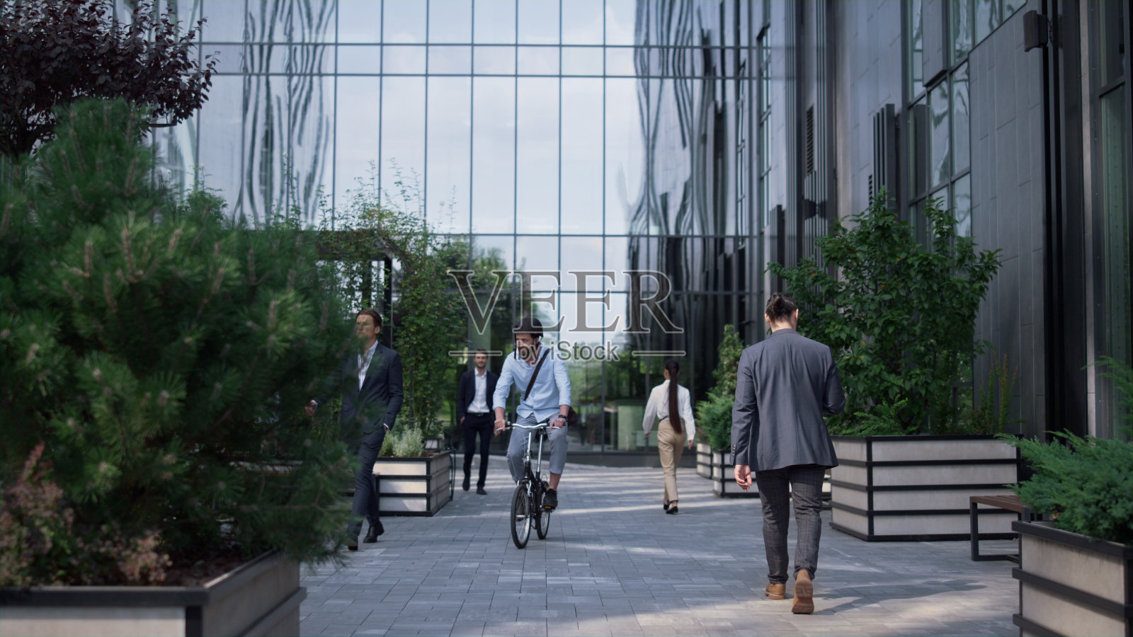 办公室经理戴着头盔在商业区骑自行车。城市机动性。照片摄影图片