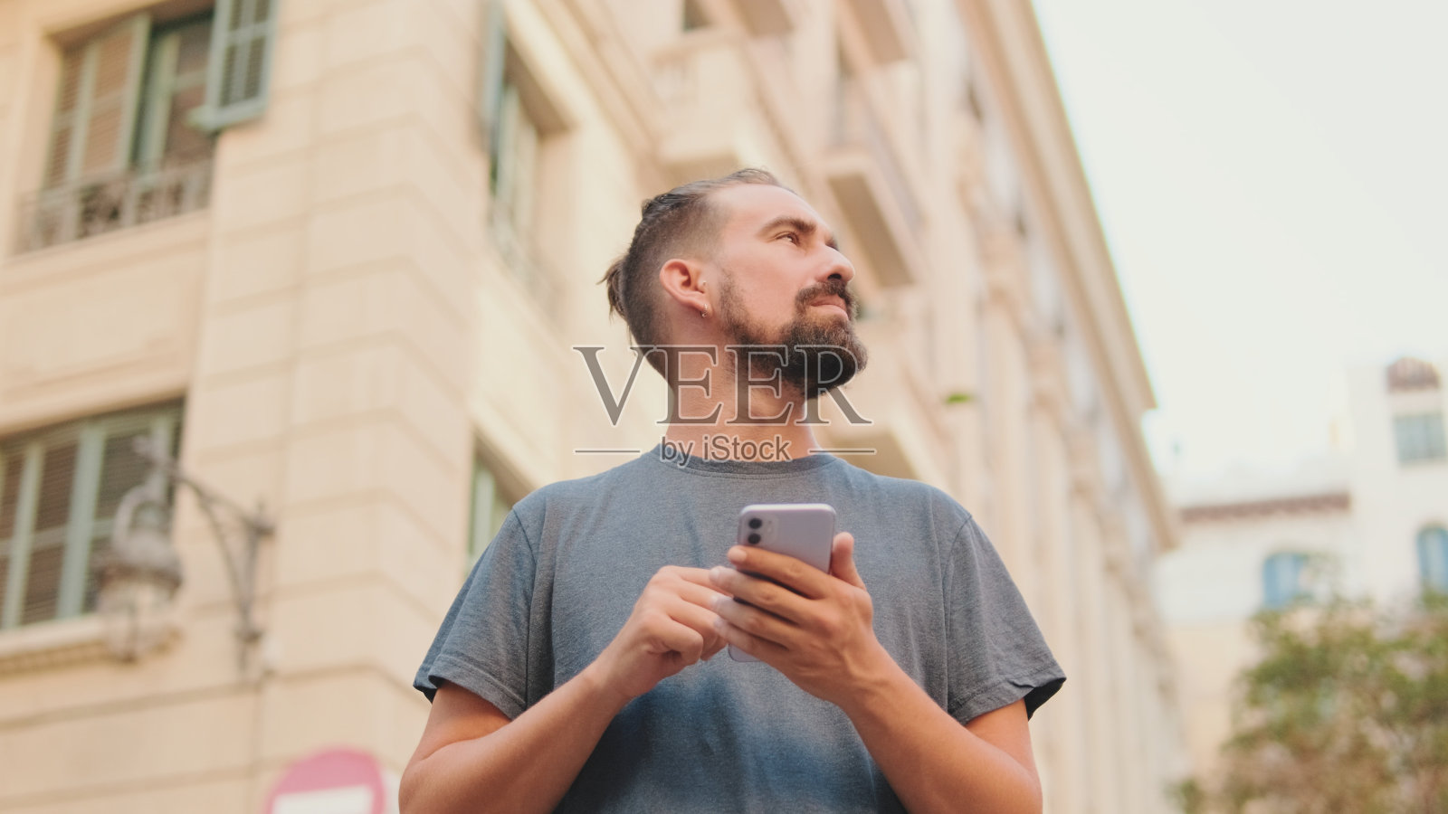 留着胡子的年轻人在手机上使用地图应用程序照片摄影图片