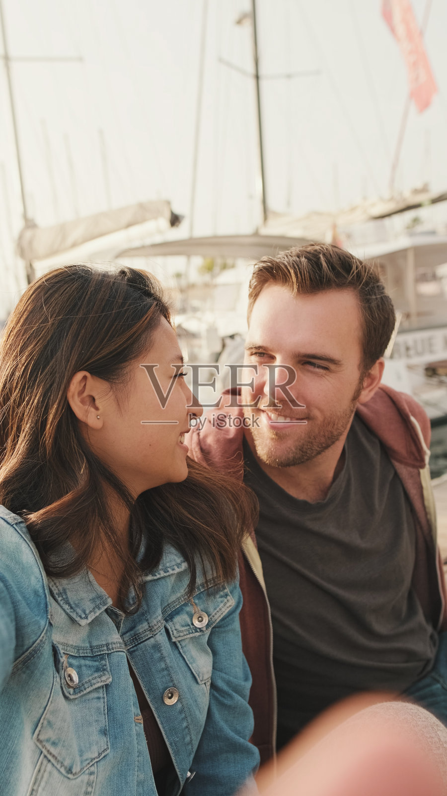 浪漫的情侣坐在游艇背景的码头上照片摄影图片