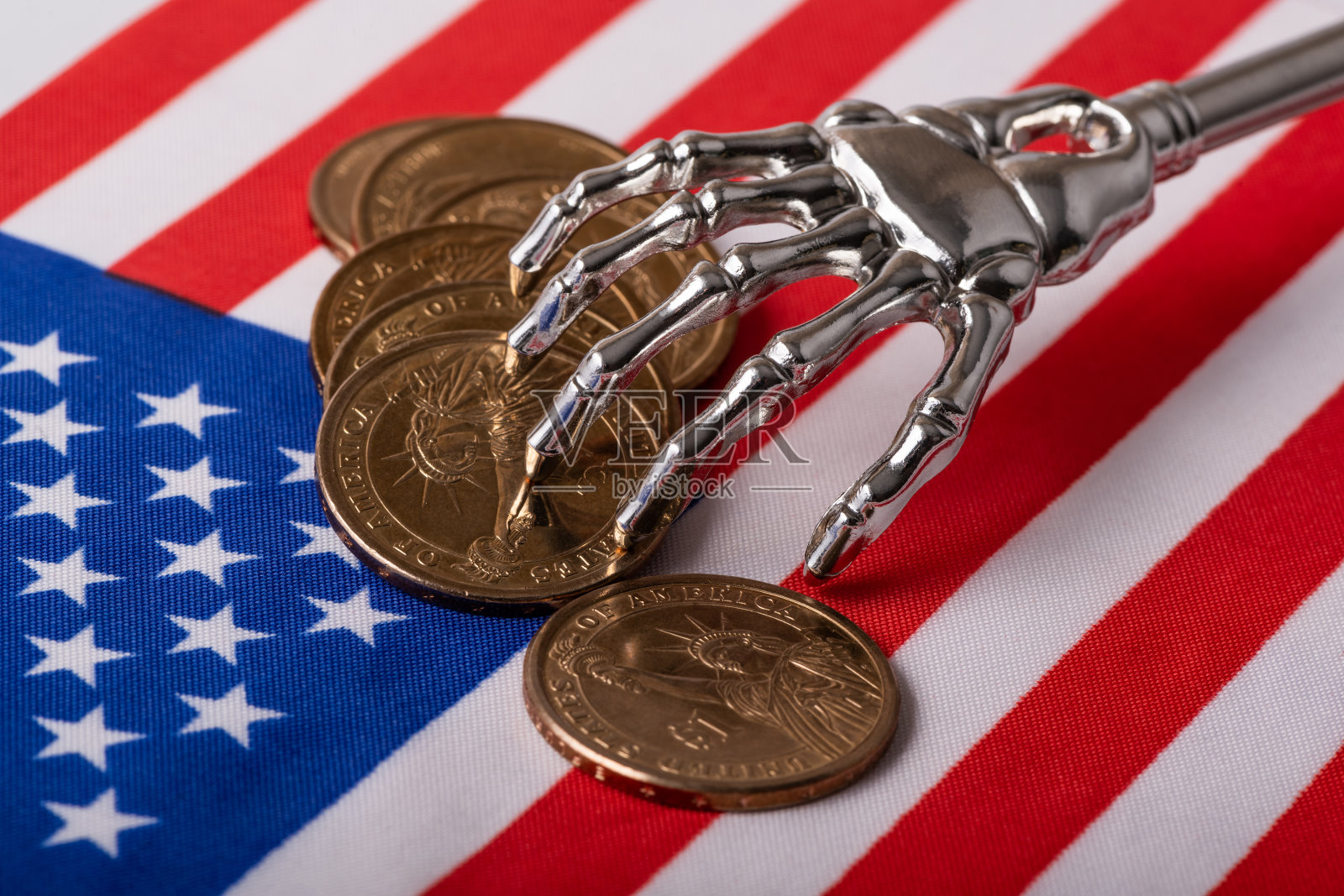 金属骨架化的人手和以美国国旗为背景的1美元面值的硬币照片摄影图片