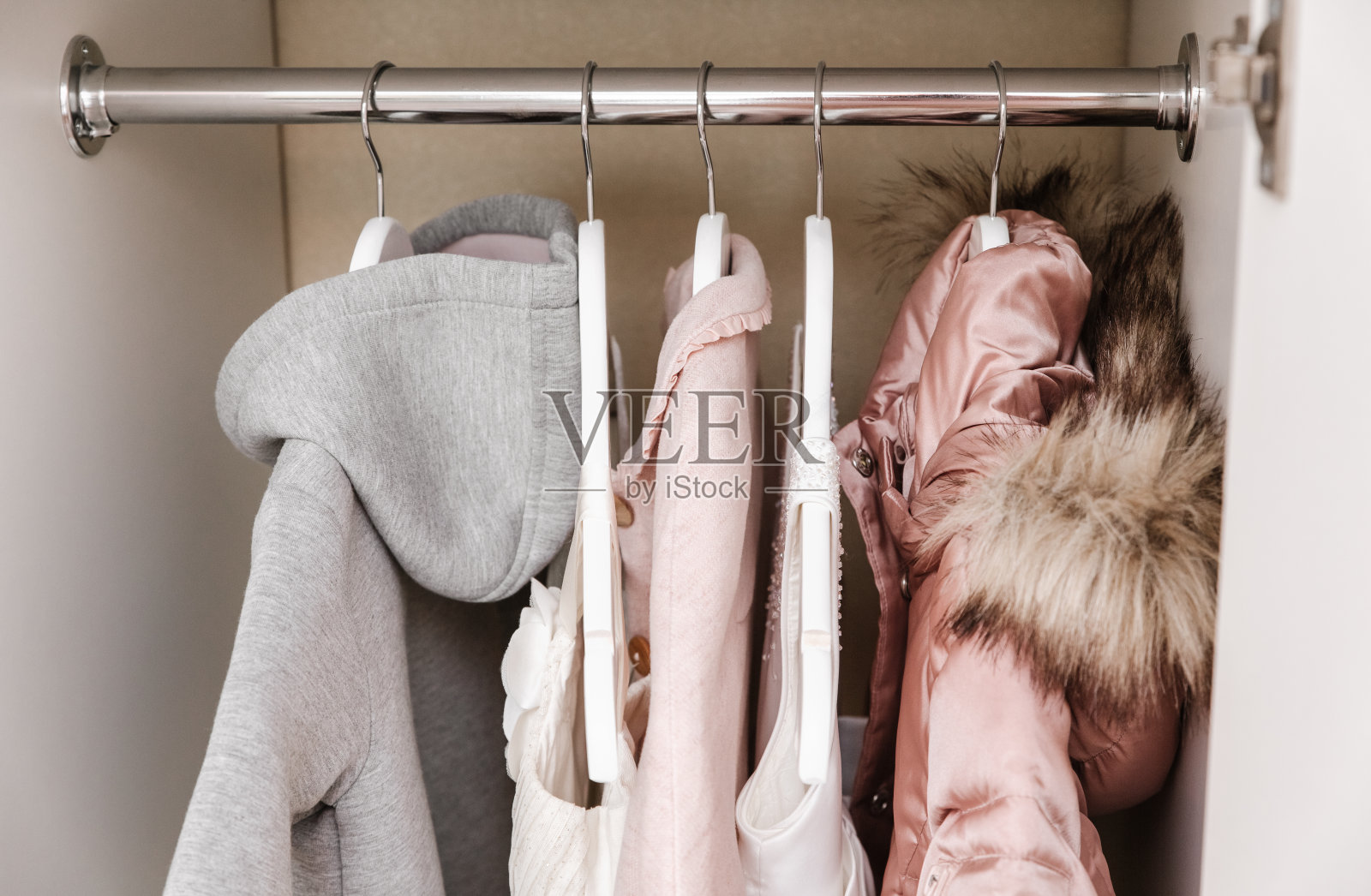 白色衣橱里为女孩准备的挂着时髦衣服的衣架。特写镜头照片摄影图片