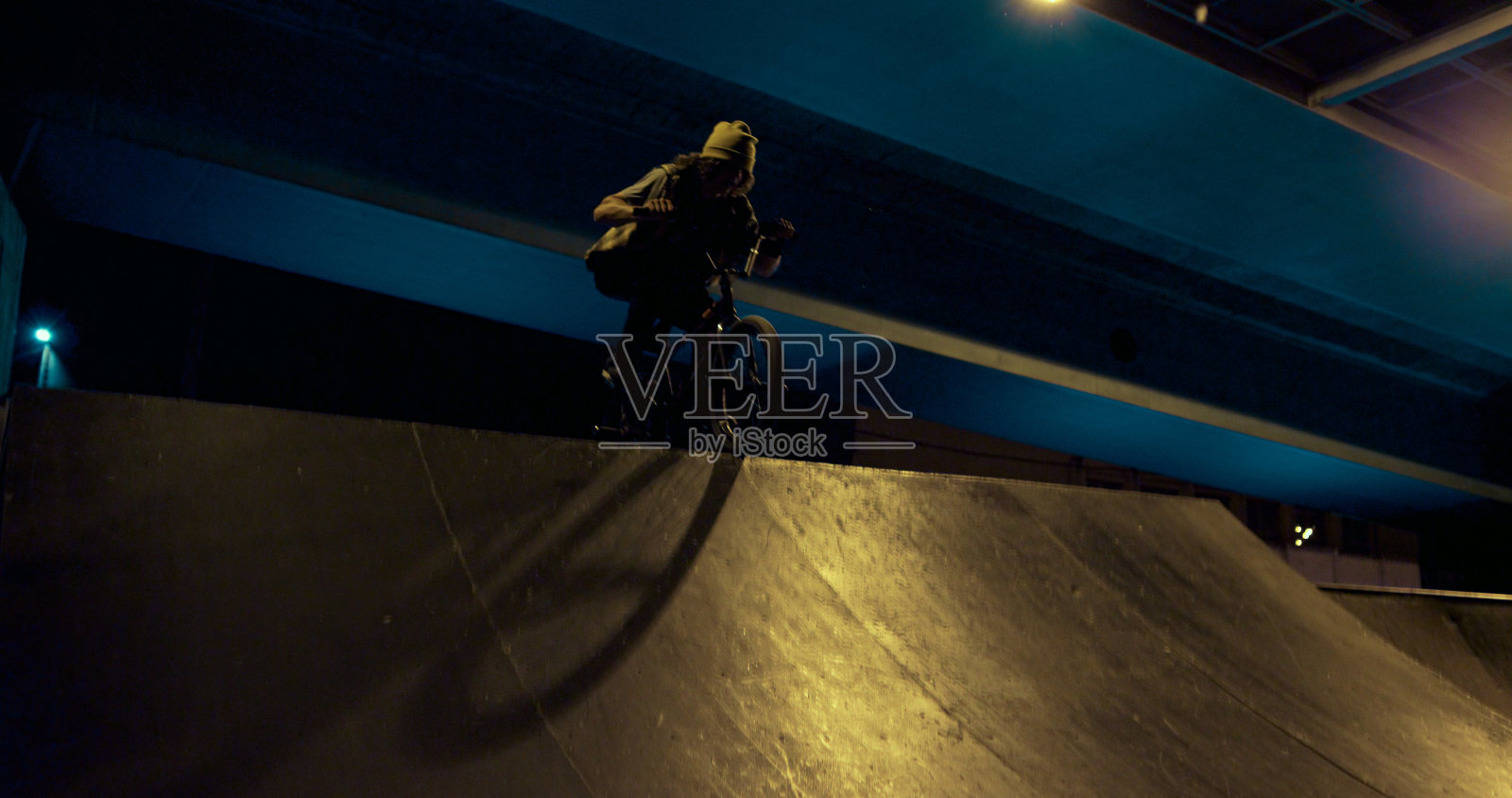 极限男子骑小轮车在城市滑板公园在晚上。小轮车骑手练习。照片摄影图片