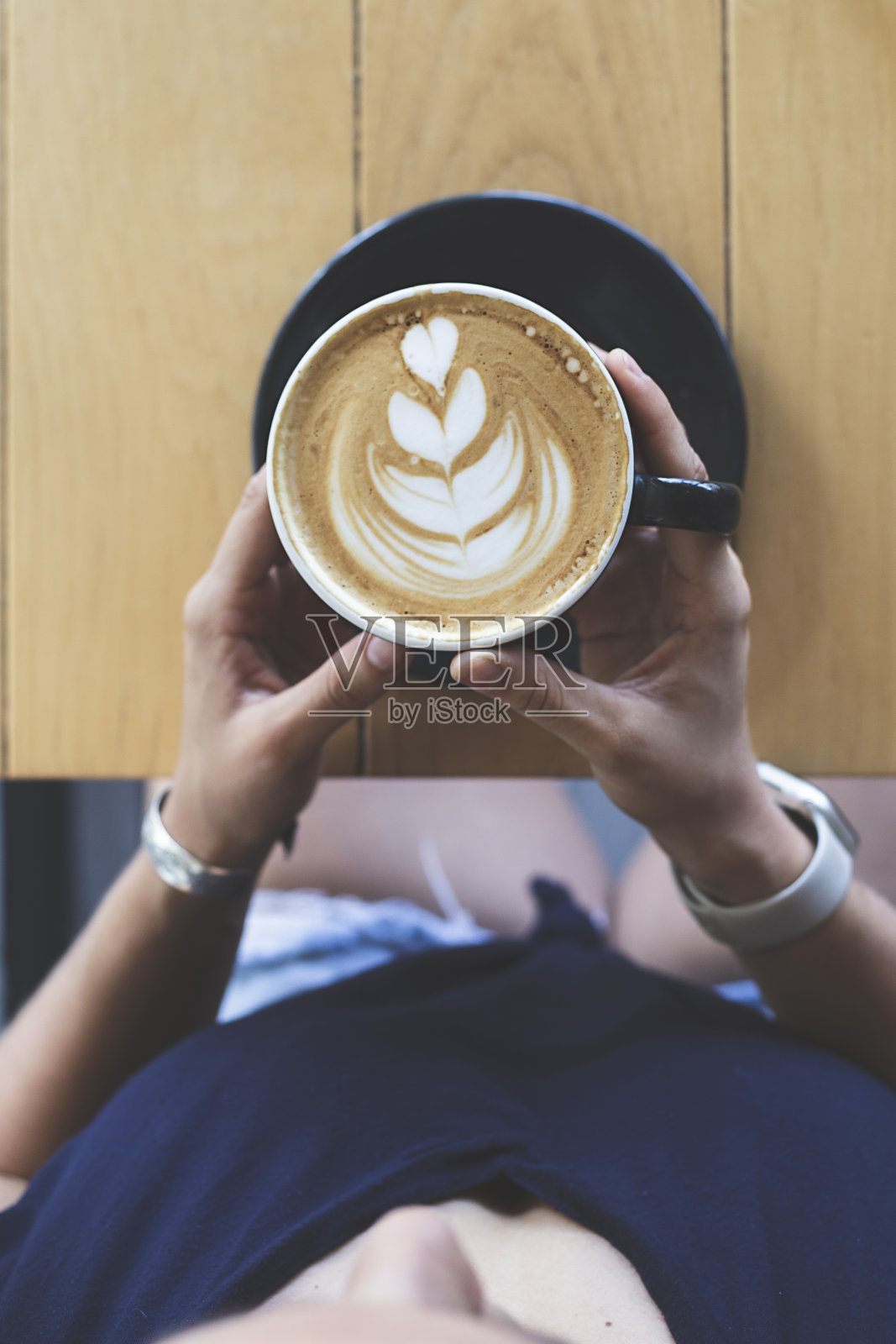 女人的手拿着一杯咖啡师准备的招牌咖啡。餐厅。安静的气氛。早餐照片摄影图片