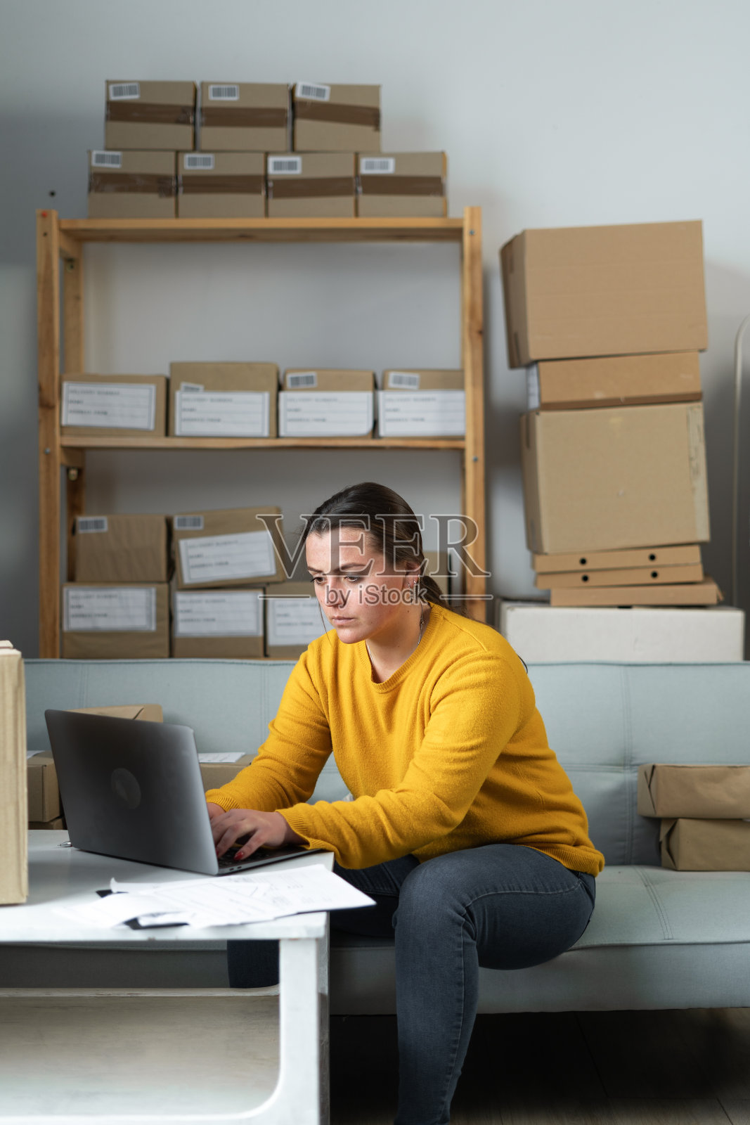 年轻认真的女人的肖像在工作场所与一个盒子在家里工作。创业小企业主，企业家，中小企业或自由职业者在线业务和交付概念。照片摄影图片