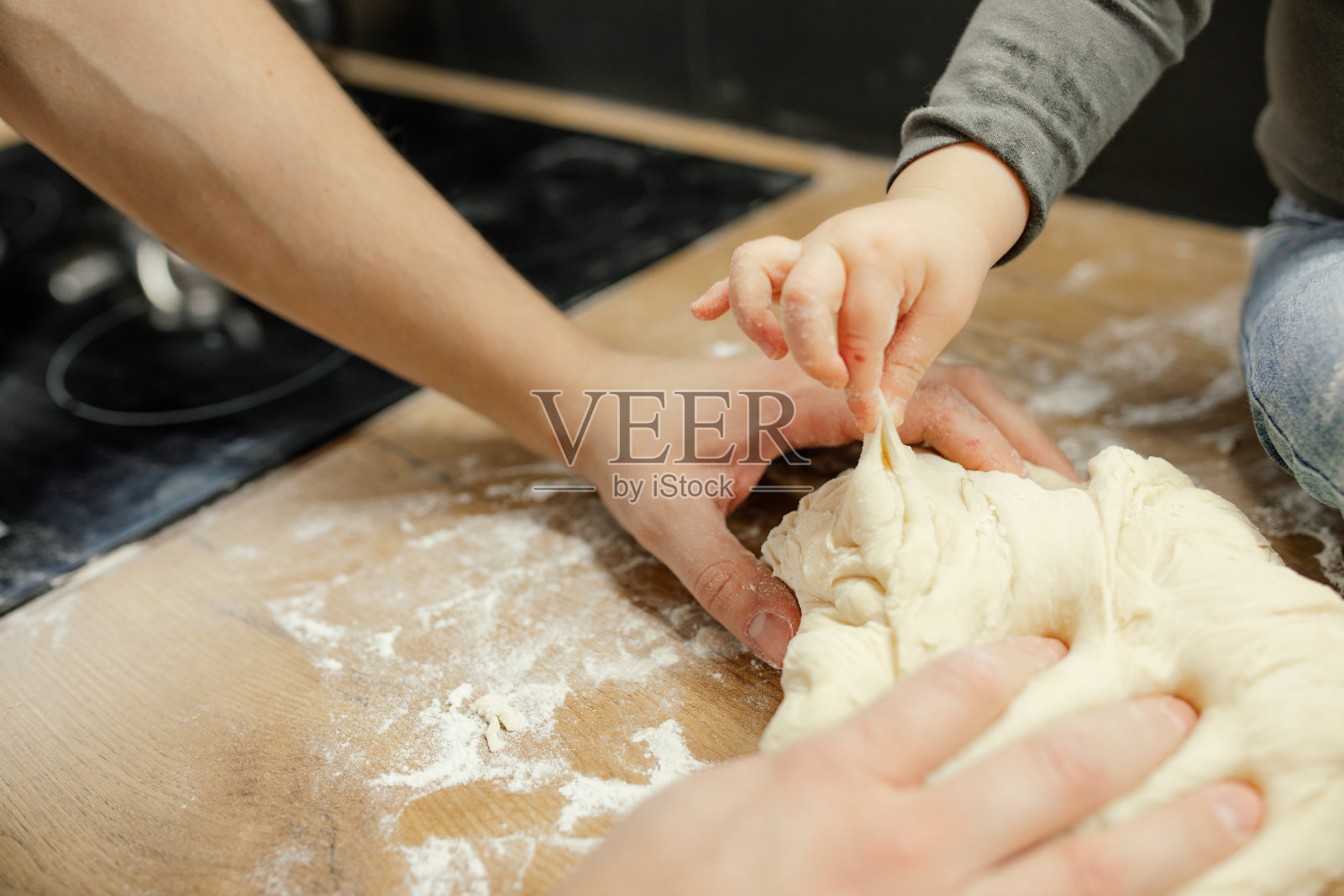 近距离剪裁的不认识的小男孩和男人的手触摸和捏一块美味的面团在木砧板上照片摄影图片
