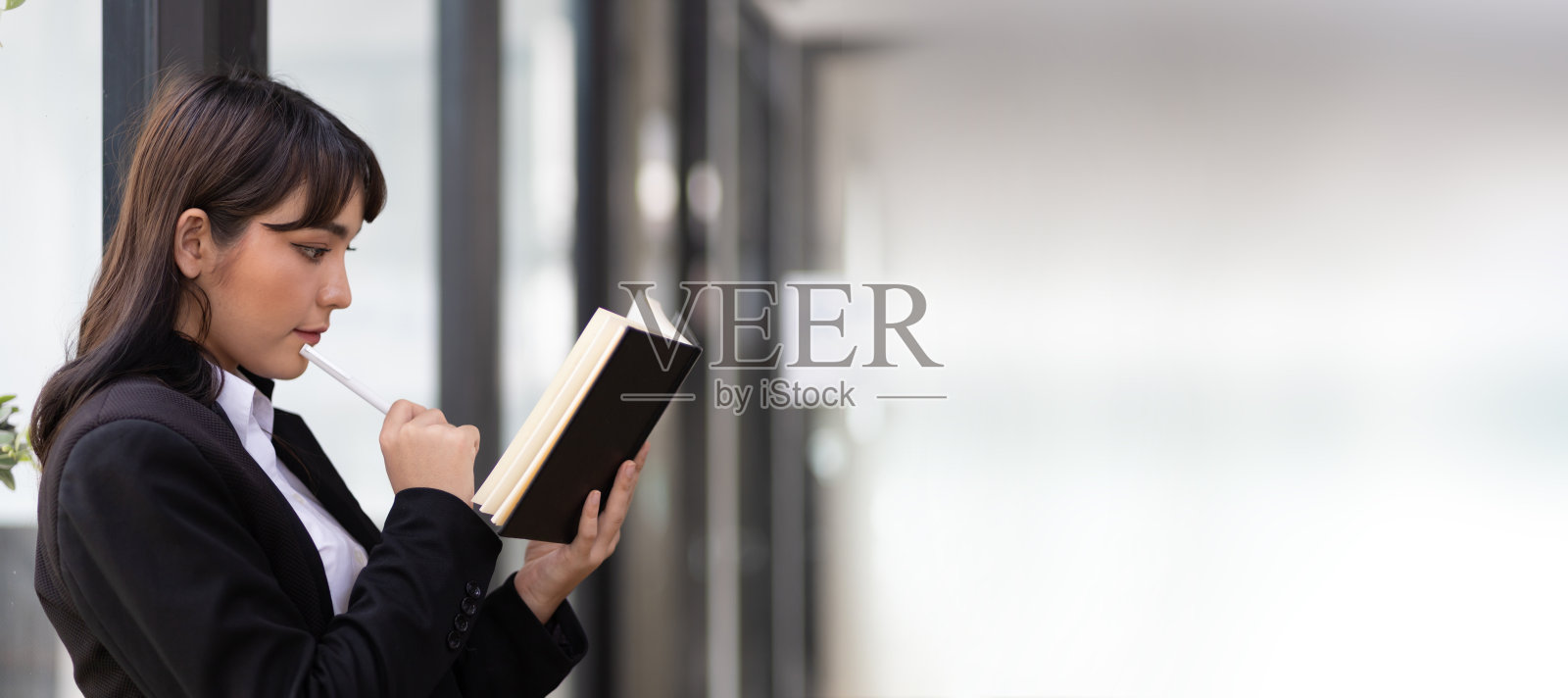 年轻迷人的亚洲女人在图书馆思考和阅读。照片摄影图片