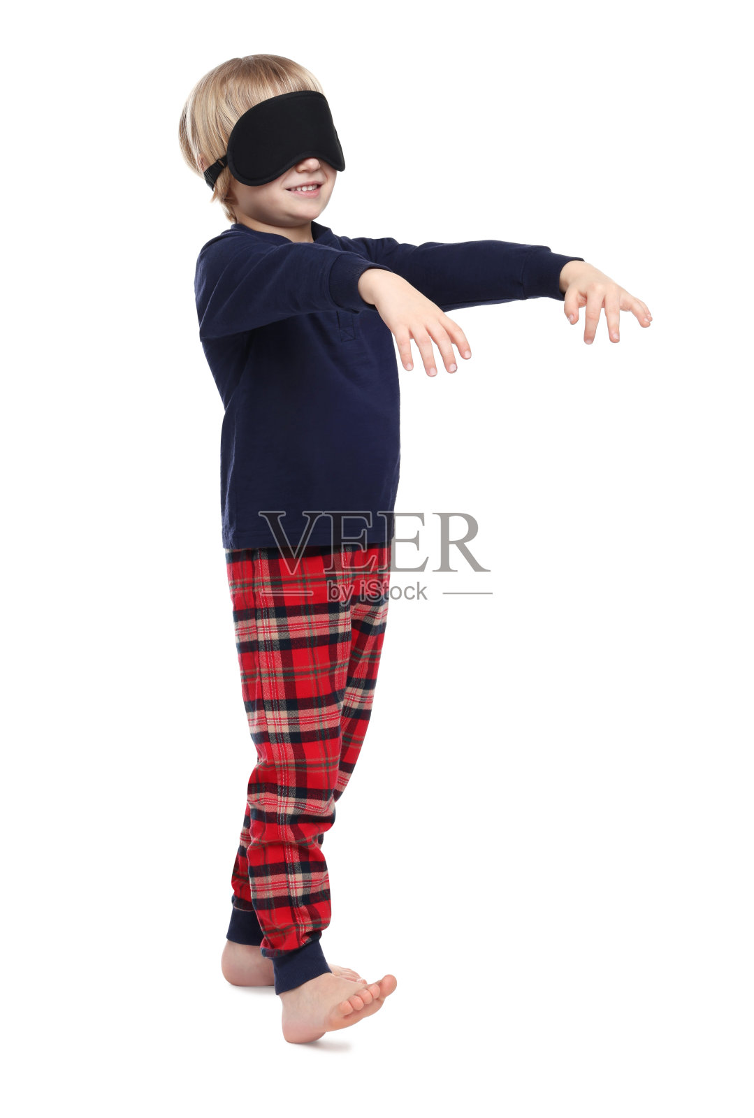 穿着睡衣和睡眠面具的男孩在白色背景上梦游照片摄影图片