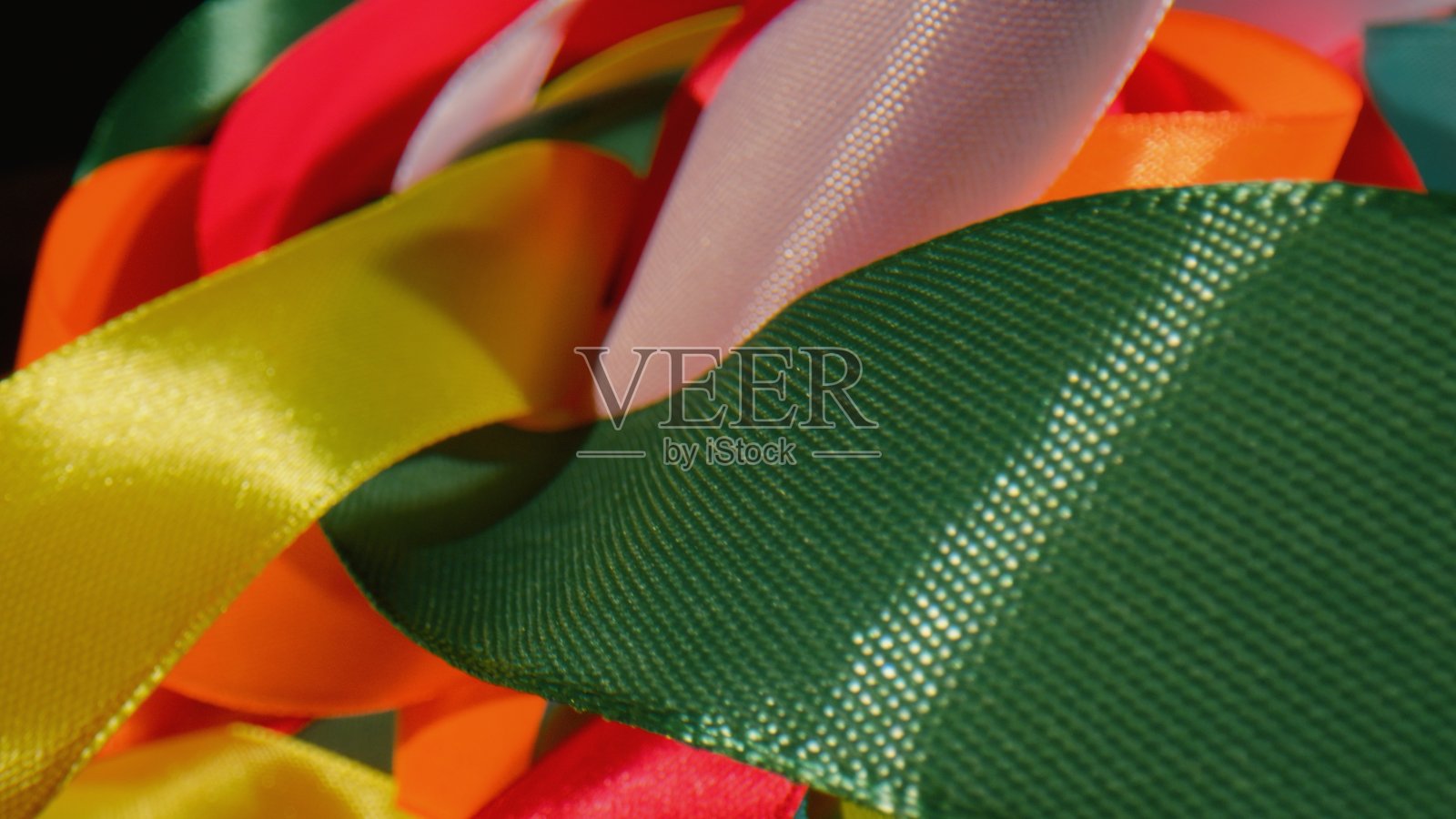 大量的丝绸扭曲的彩色明亮的丝带-接近照片摄影图片