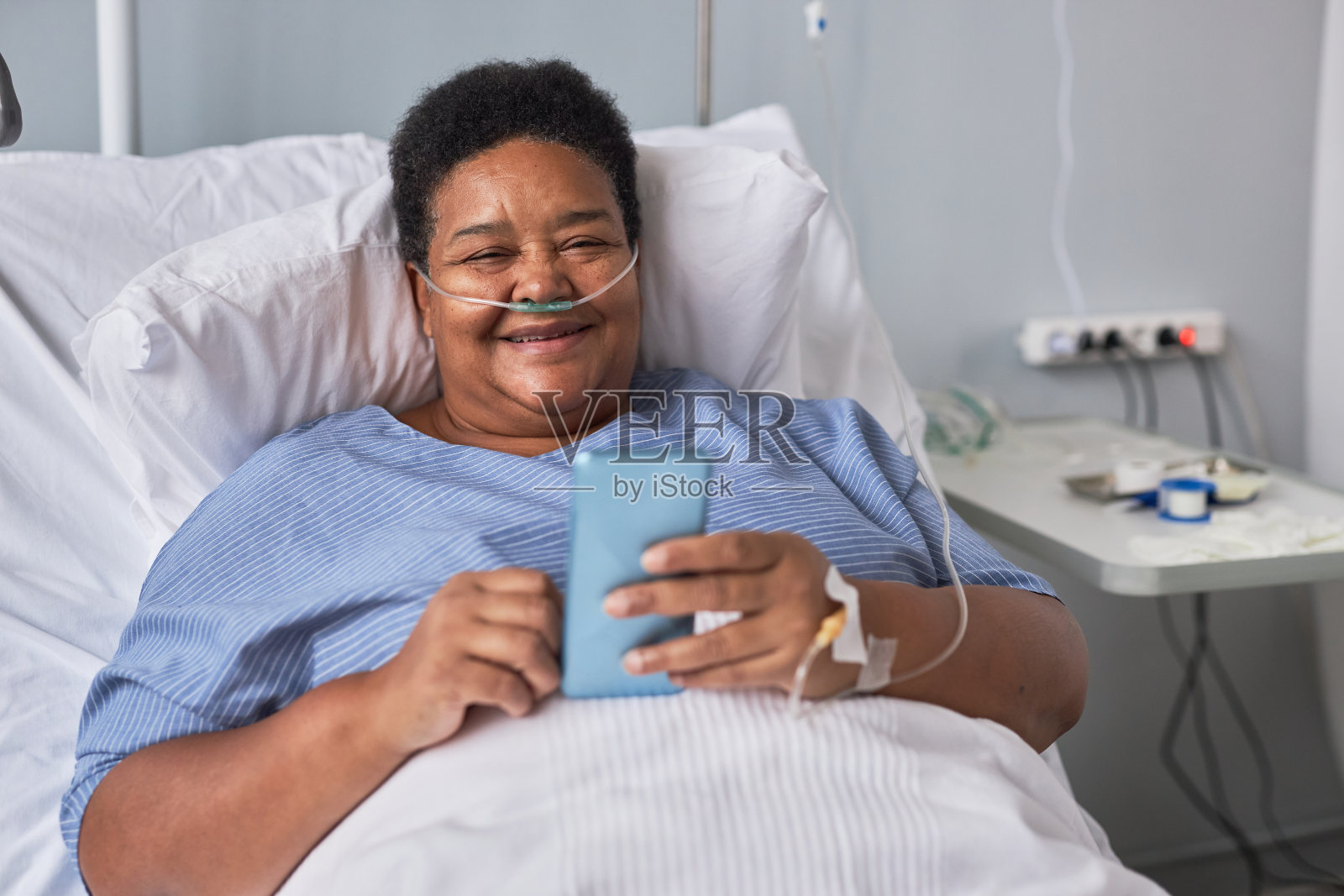 笑容满面的老年妇女躺在病床上打电话照片摄影图片