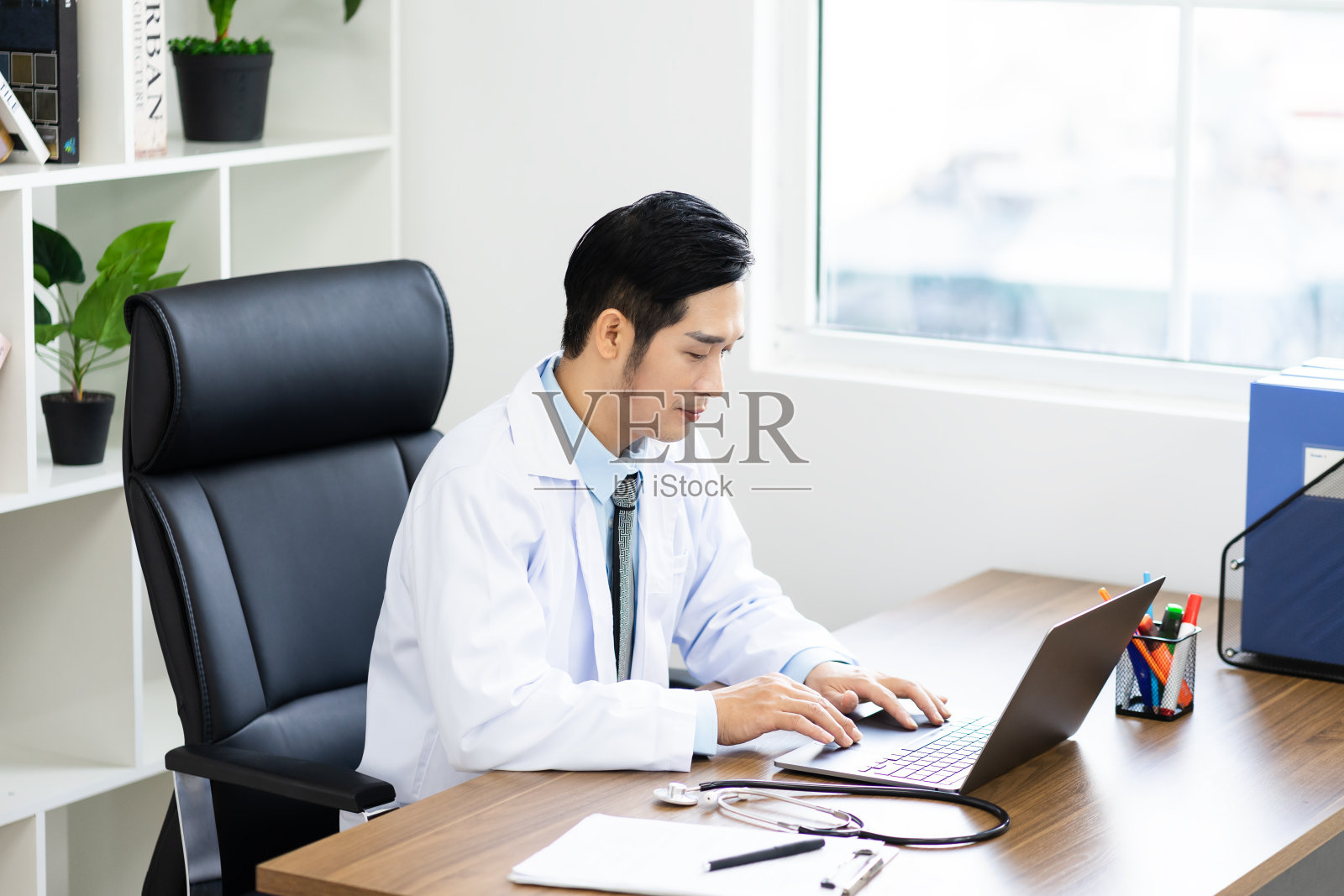 亚洲男性医生肖像坐在工作中照片摄影图片