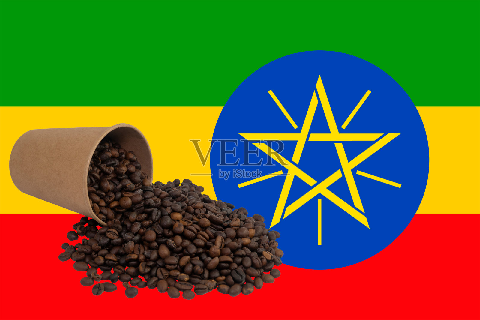 在埃塞俄比亚国旗的背景下，翻倒的一次性纸杯里装满了烘焙好的咖啡豆照片摄影图片