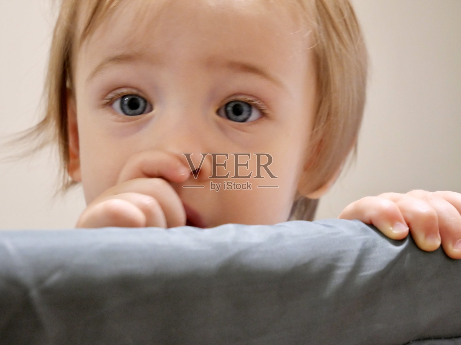 蓝眼睛的女婴吮吸着她的拇指照片摄影图片