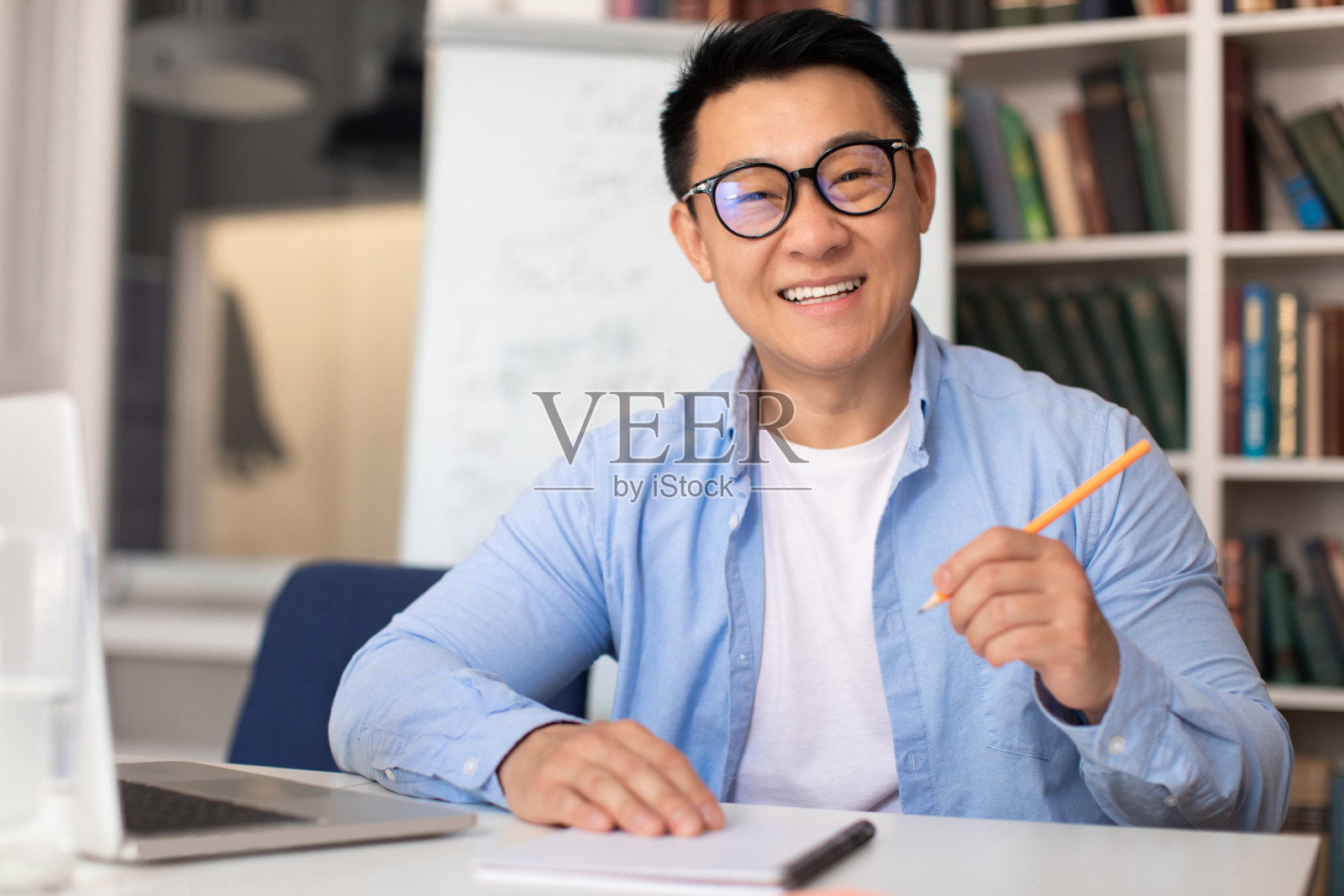 快乐的韩国家庭教师在室内在线课堂上做笔记照片摄影图片