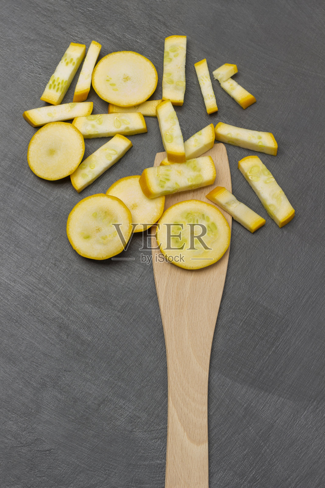 切好的黄色西葫芦放在勺子里，放在桌子上。照片摄影图片