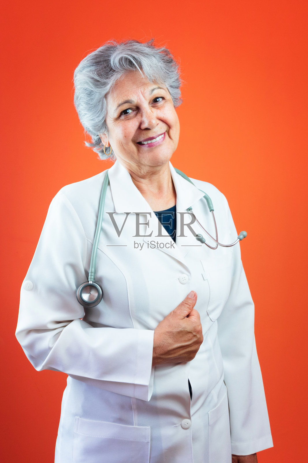 保健生活方式-成熟的巴西医生或兽医妇女与听诊器隔离在橙色背景照片摄影图片