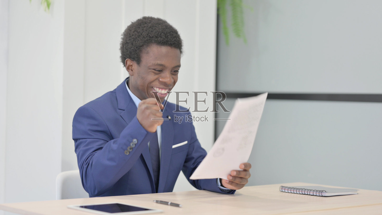 非洲商人在办公室阅读文件时庆祝成功照片摄影图片