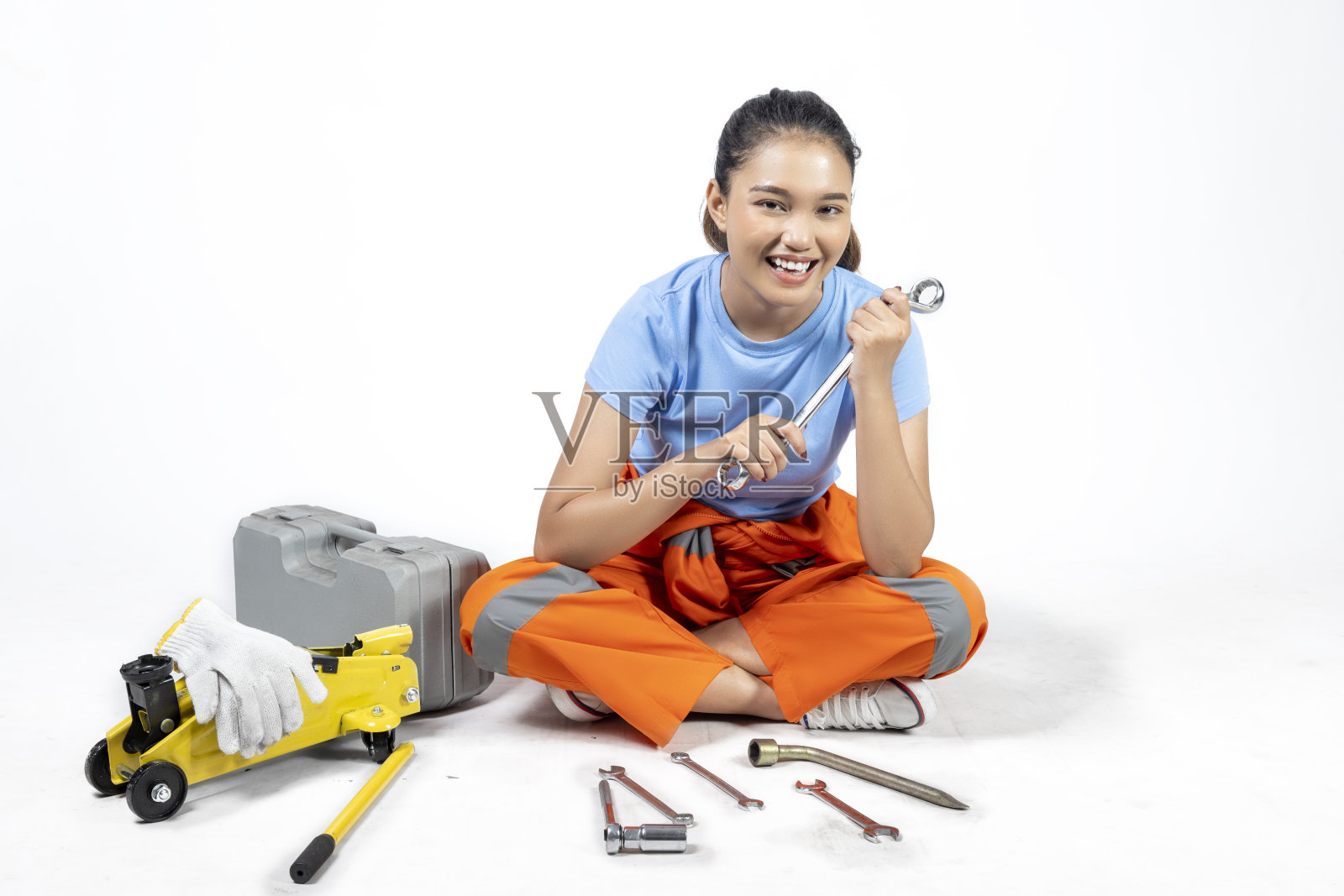 穿着制服的亚洲妇女汽车技师坐在汽车千斤顶和工具箱和扳手照片摄影图片