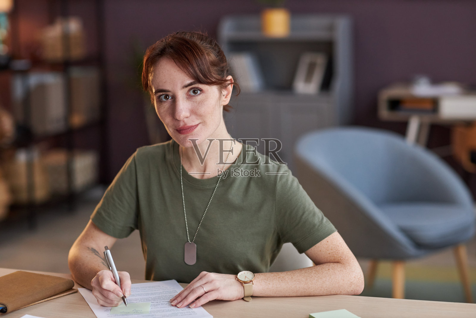 年轻的女军人在办公室办公桌前工作，看着相机照片摄影图片