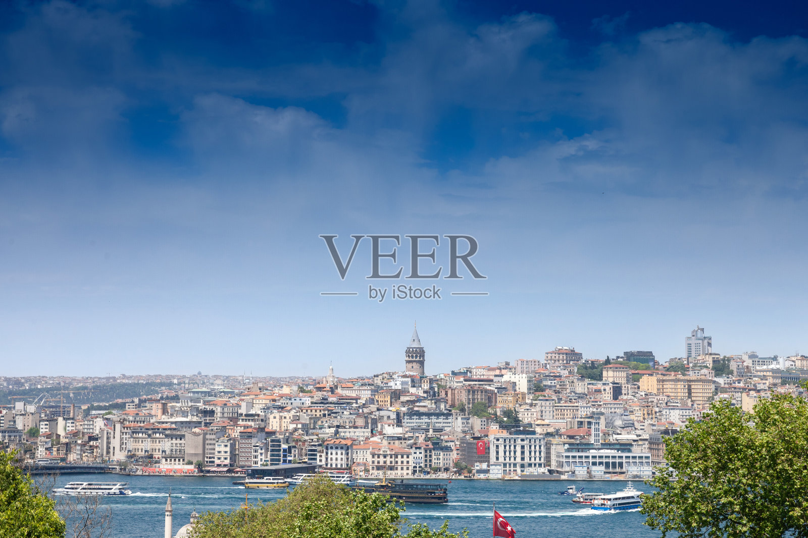 在一个阳光明媚的下午，在卡拉科伊拍摄的Beyoglu区全景，山上的加拉塔塔，前景是博斯普鲁斯海峡，土耳其伊斯坦布尔。照片摄影图片