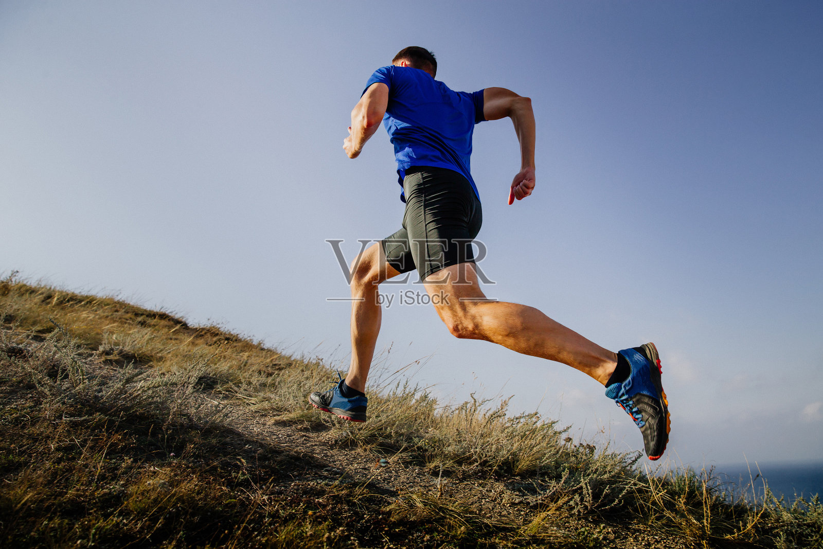 运动员在天空背景下跑山路照片摄影图片