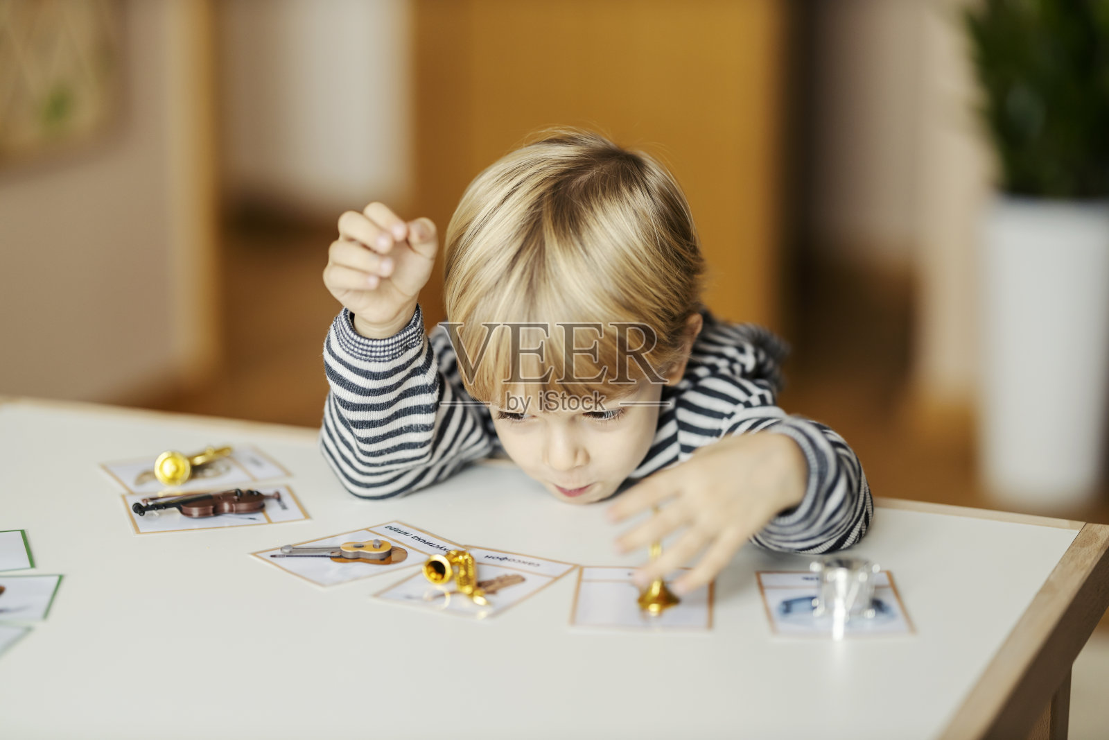 一个小男孩在幼儿园玩玩具和学习乐器。照片摄影图片