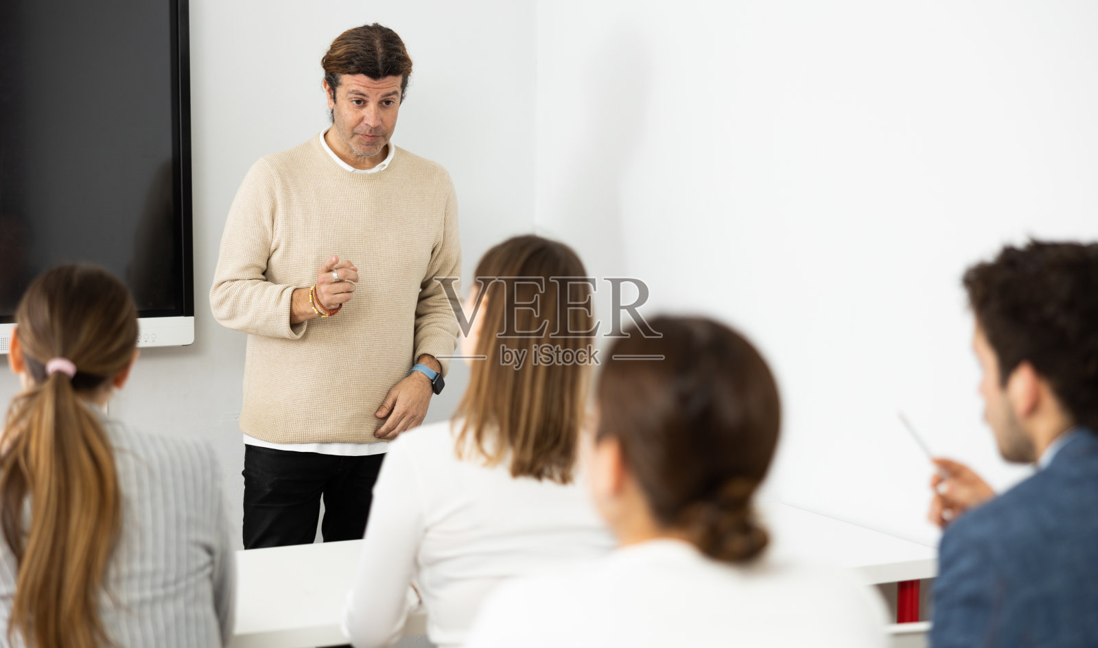 在互动板旁的中年男老师在教室里给一群学生讲解规则。外语学习的概念照片摄影图片