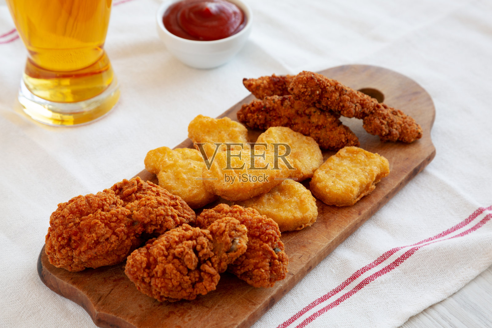 美味的快餐:鸡块，鸡翅和嫩鸡配番茄酱和啤酒，侧视图。照片摄影图片