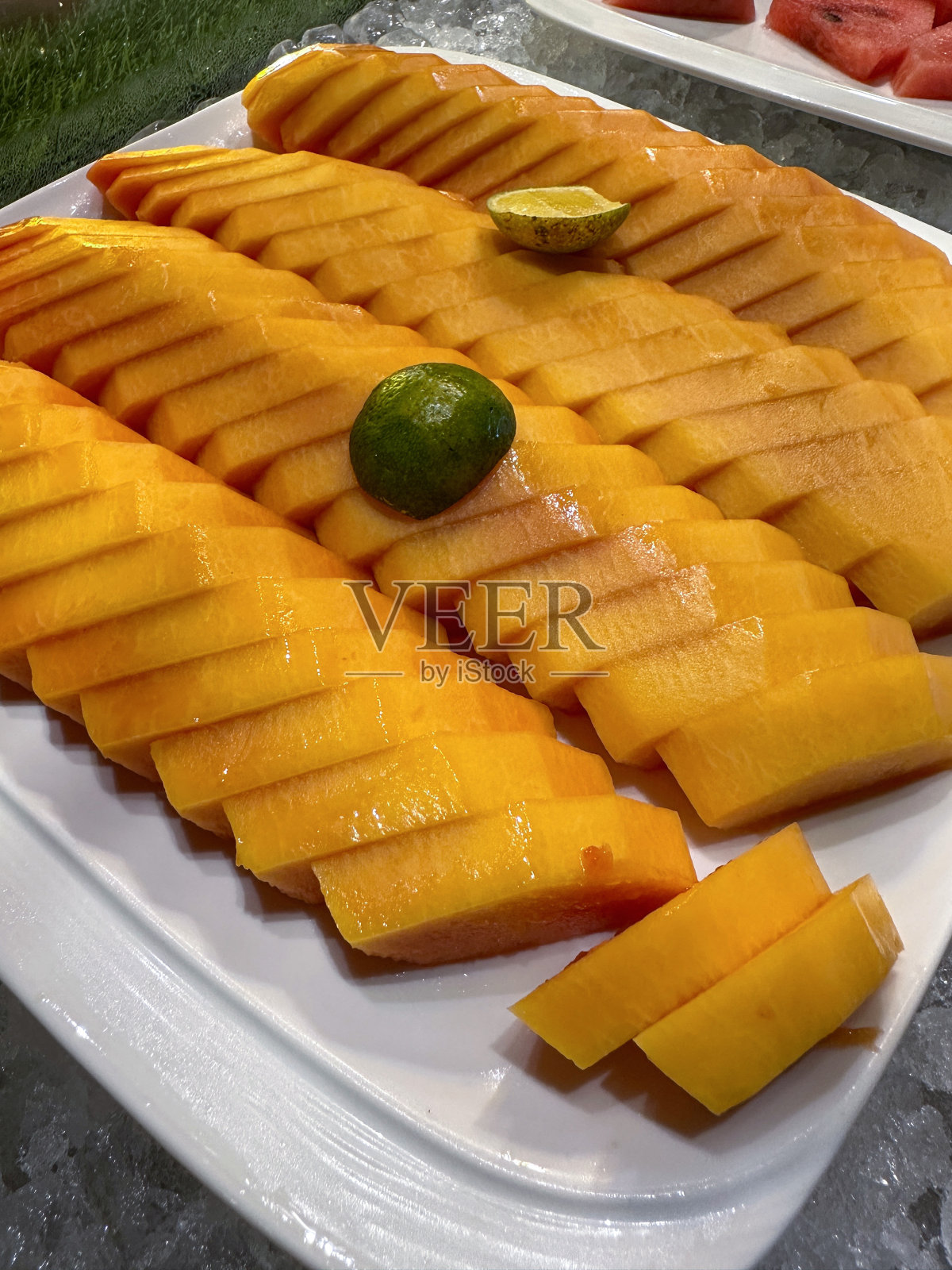 酒店自助早餐自助展示的图片，白色的盘子里有一排排的木瓜(木瓜)，自制水果沙拉的配料，视野开阔，重点在前景照片摄影图片