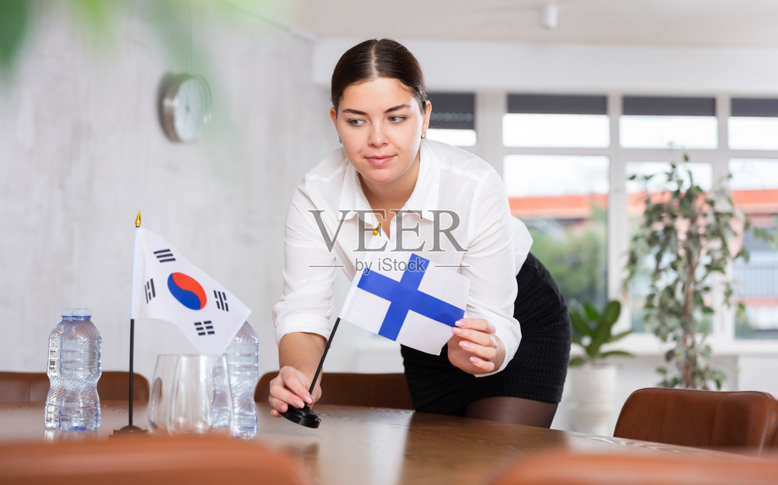 年轻的女服务员为韩国和芬兰的国际谈判举旗照片摄影图片