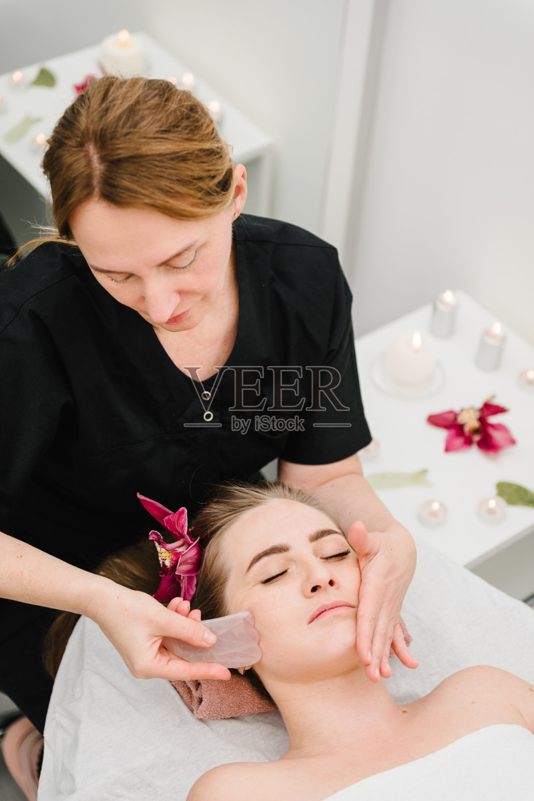 面部护理，护肤理念。美容师在水疗沙龙为客户做面部恢复程序。刮痧、刮刀装置用于面部按摩治疗。美观美容，呵护面部。照片摄影图片