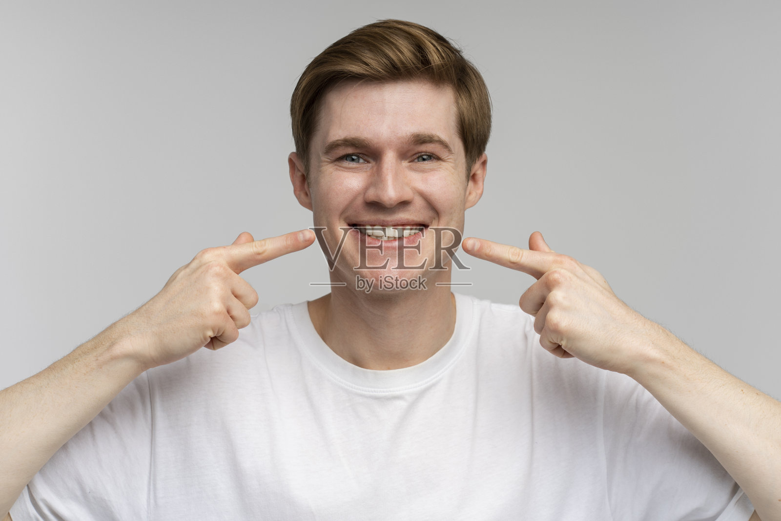 肖像的快乐开朗的人指着食指微笑显示白色的牙齿照片摄影图片