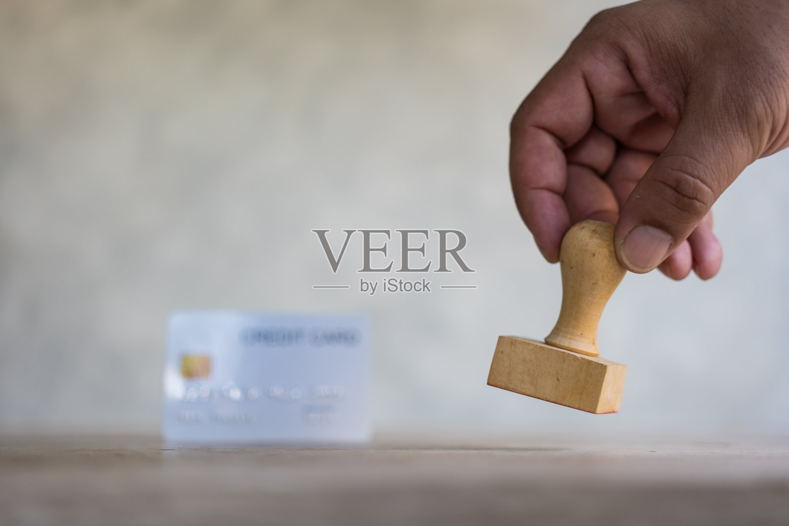 手用橡皮图章和带有模糊背景的白色信用卡。照片摄影图片