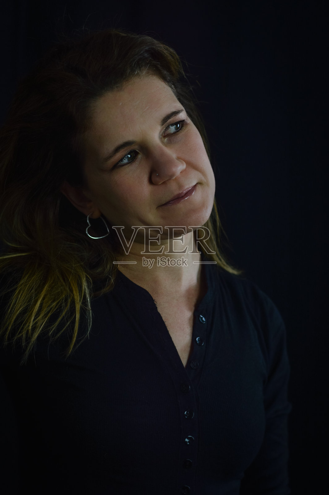 一个美丽的金发女人的肖像谁看起来好奇侧倾斜她的头照片摄影图片