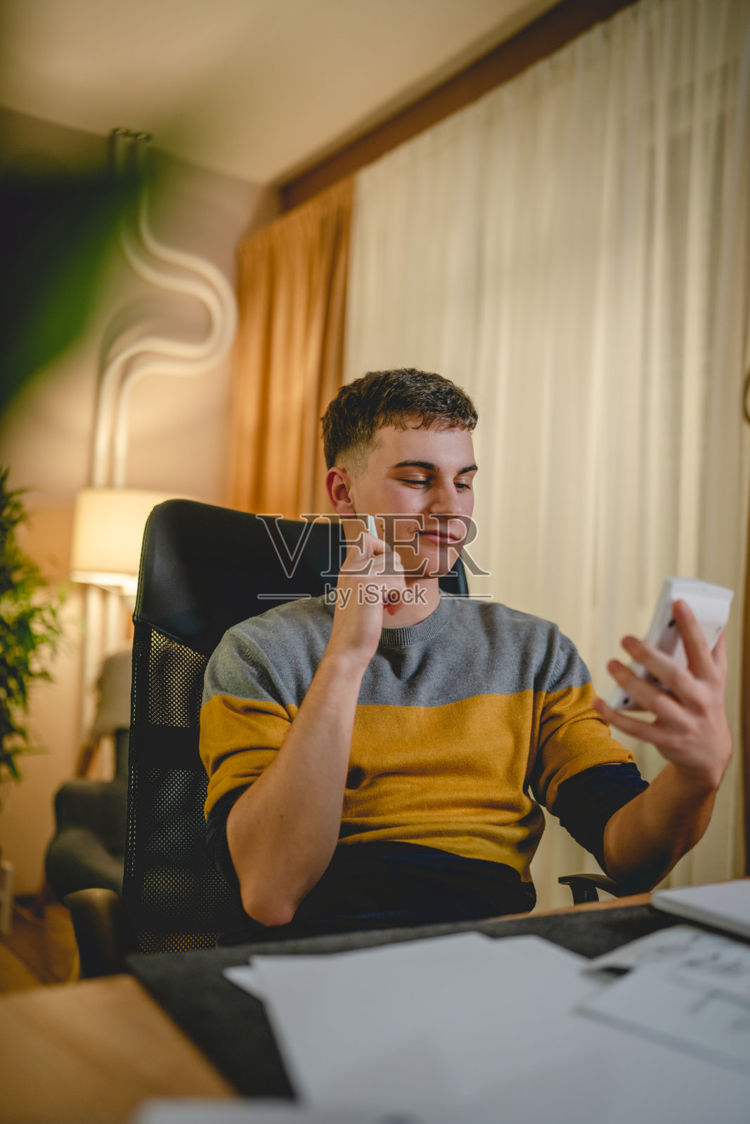 年轻的白人男子，十几岁的学生，晚上在家里的桌子上学习照片摄影图片