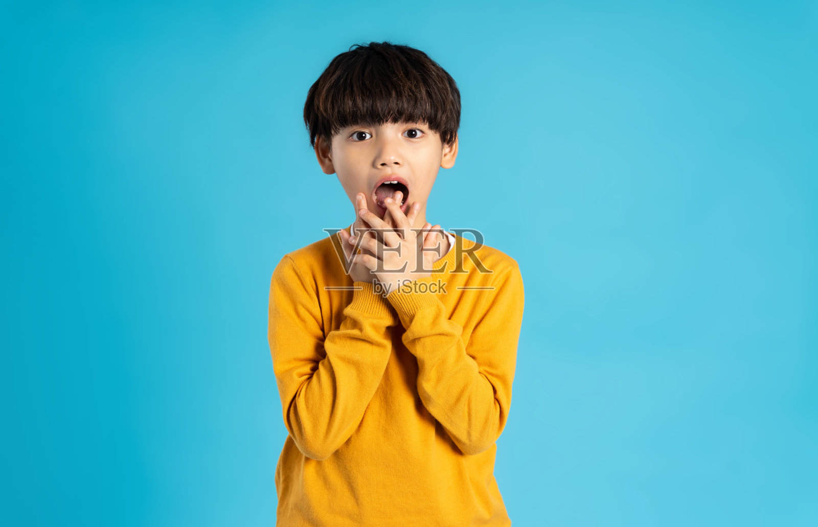 亚洲男孩在蓝色背景上摆姿势的肖像照片摄影图片