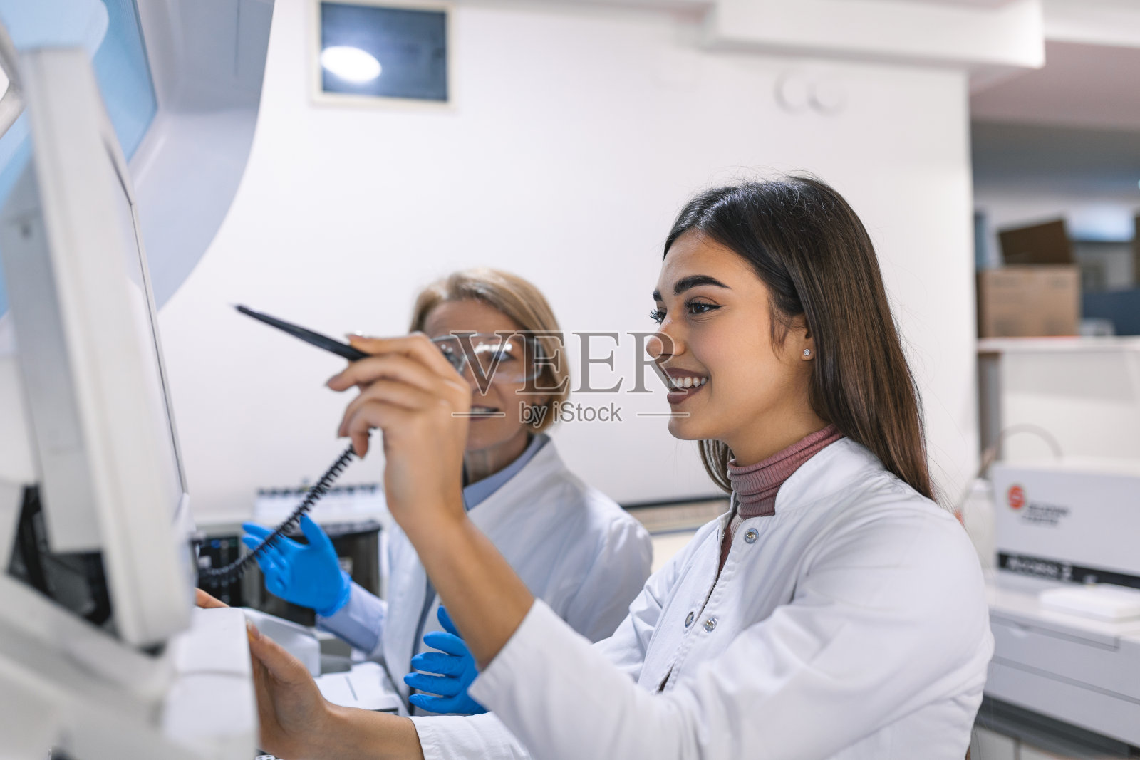 两名研究科学家用平板电脑为医疗设备编程。在现代化实验室从事药物研究的专业人员队伍。照片摄影图片