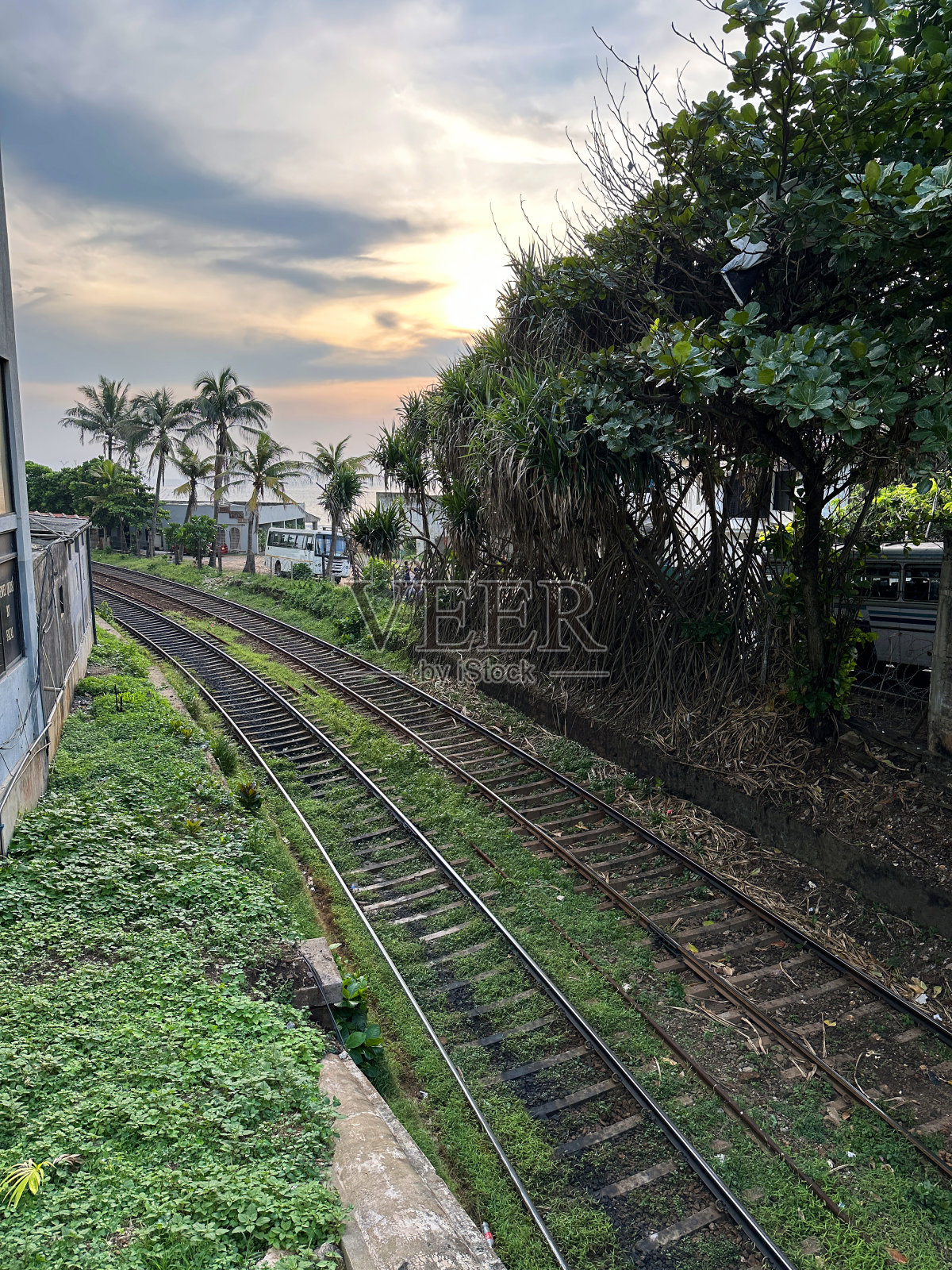 海岸线(南线)铁路线与高速公路和海岸线平行，金属铁轨和长满杂草的砾石，斯里兰卡科伦坡主干道上的汽车，包括汽车和小巴，高架视图照片摄影图片