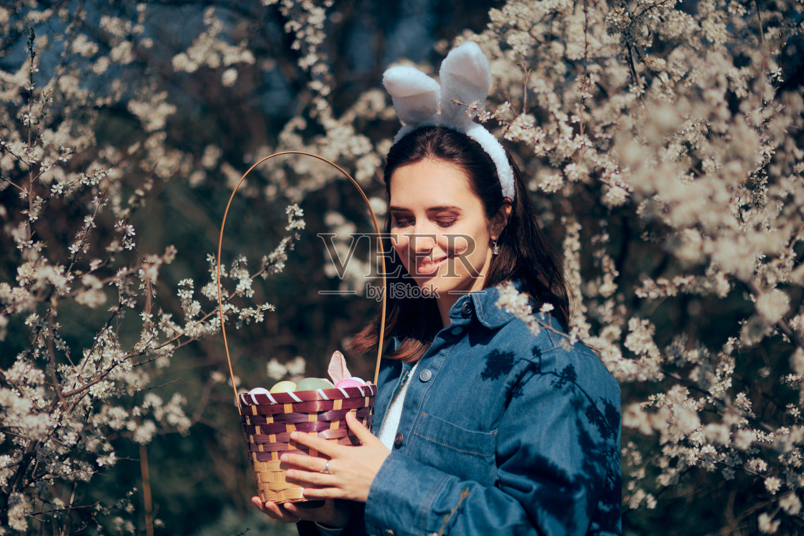 带着一篮子复活节彩蛋和兔子耳朵的快乐女人照片摄影图片