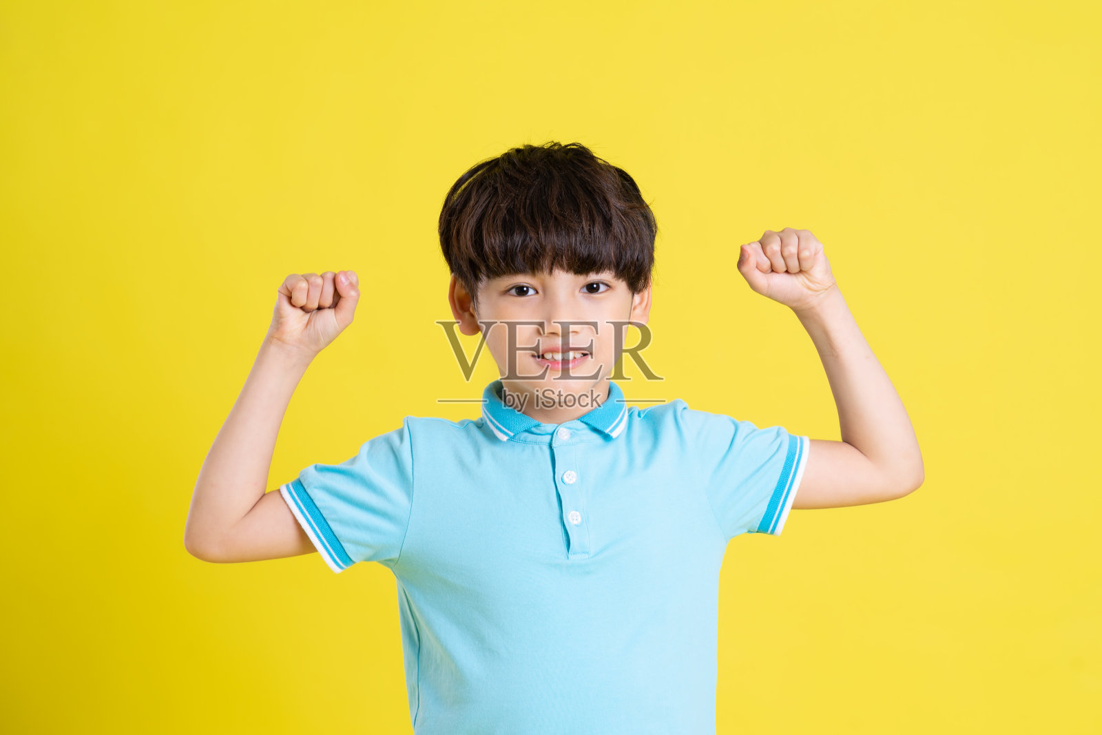 一个亚洲男孩在黄色背景上摆姿势的肖像照片摄影图片