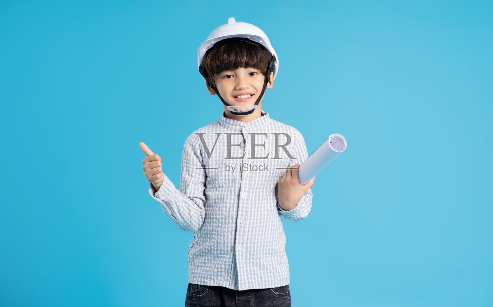 亚洲男孩扮演工程师的角色，孤立在蓝色背景上照片摄影图片