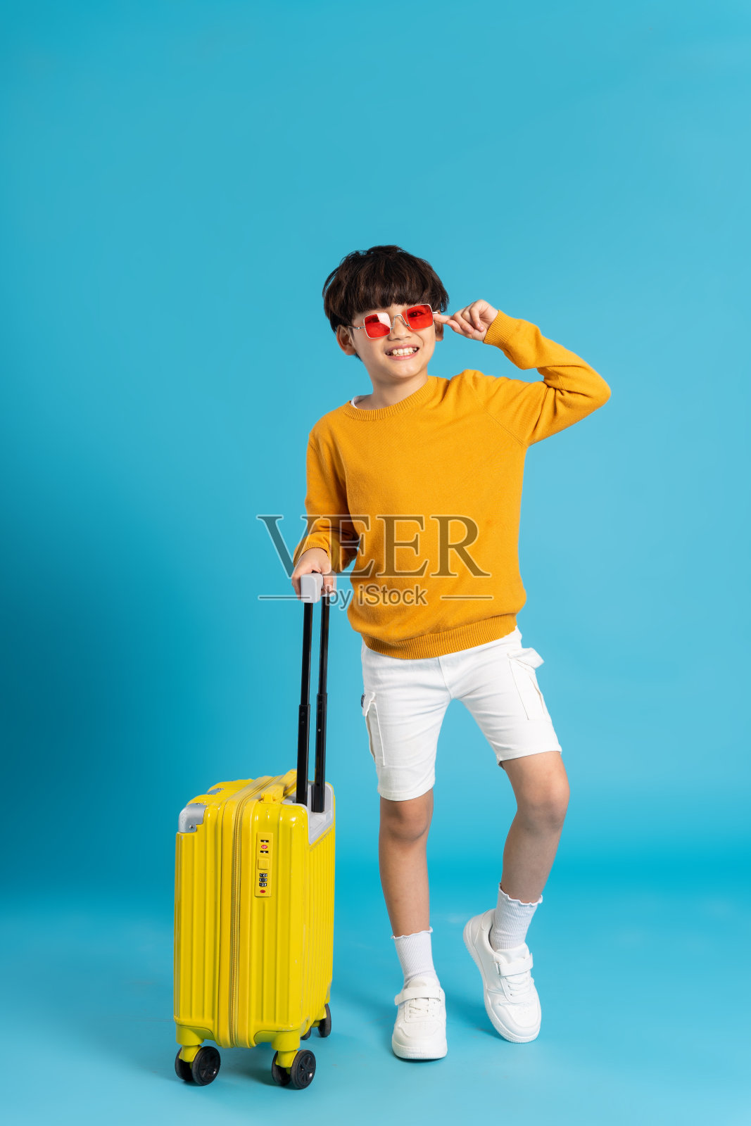 亚洲男孩拉着蓝色背景的手提箱照片摄影图片