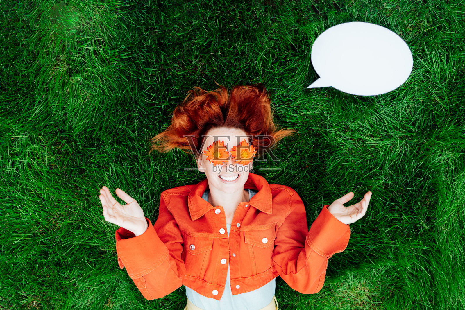 哇。情绪惊讶，震惊的红头发女人与红橙色非洲菊花眼镜和空白的思想模型云在绿色的草地。积极情绪。时尚。选择性聚焦，复制空间。照片摄影图片