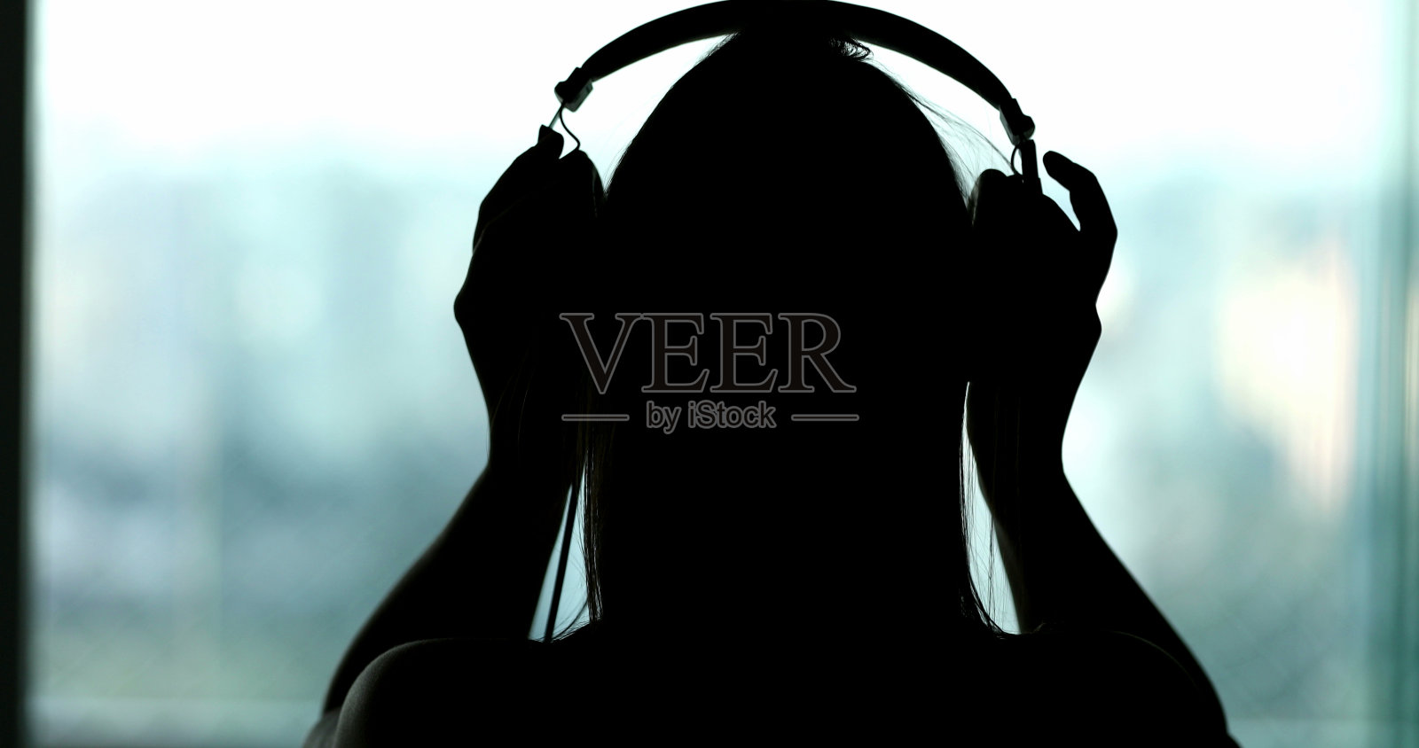 剪影女人听音乐，播客，或有声读物。摘掉耳机的人照片摄影图片