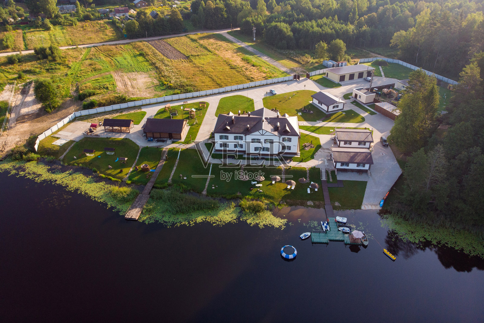 一个美丽的湖和一个位于美丽的阳光灿烂的森林中央的乡村别墅。前视图。航空摄影照片摄影图片