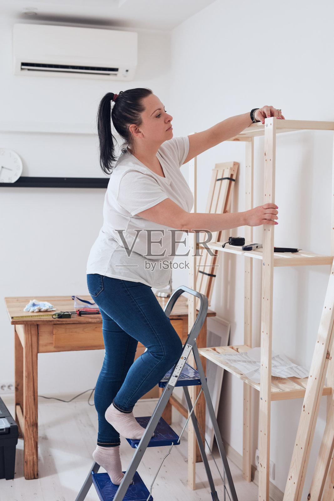在公寓里组装新木架和家具的女人。照片摄影图片