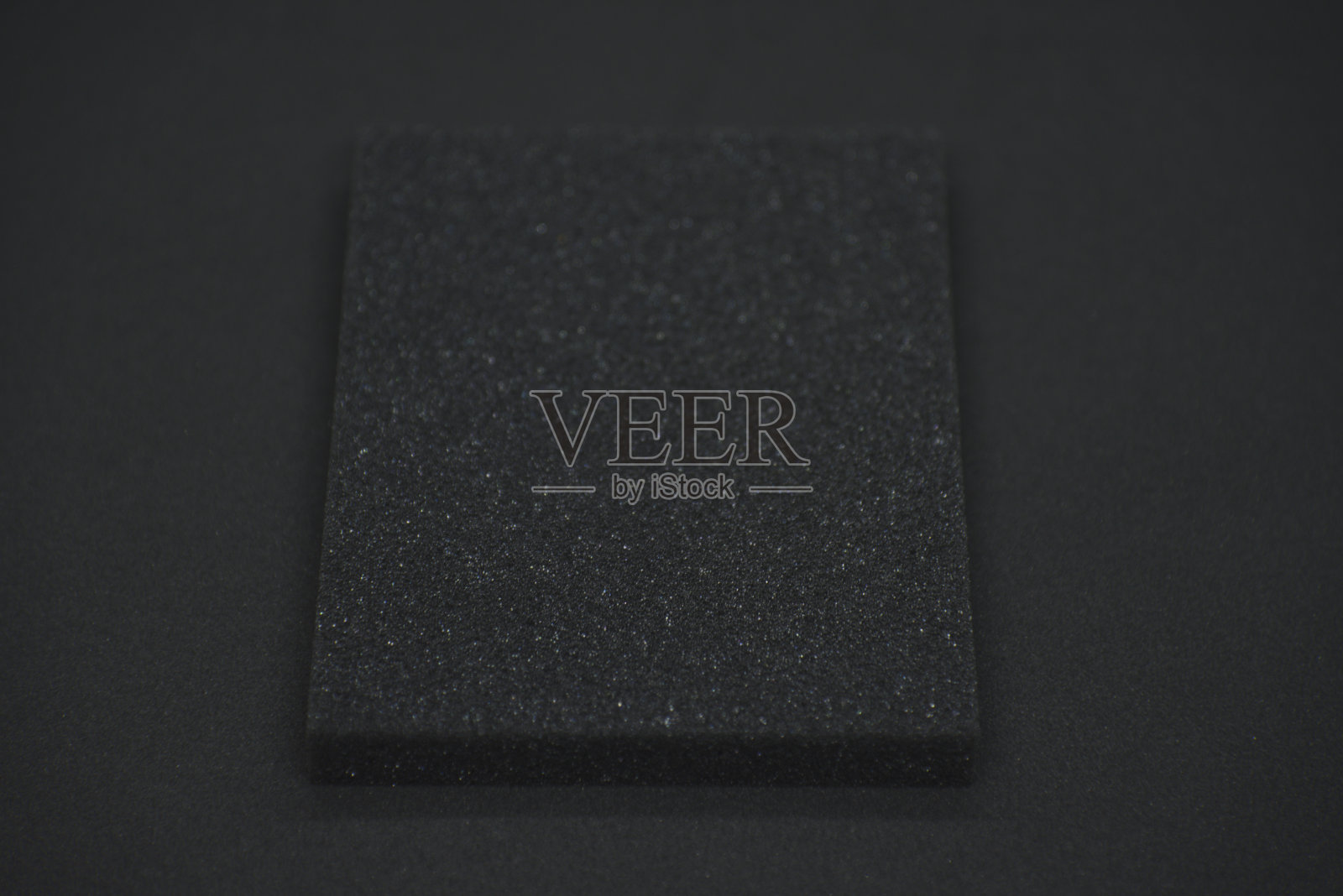 黑色背景上的黑色海绵。黑色泡沫橡胶在黑布上。垫片的黑色方形。照片摄影图片