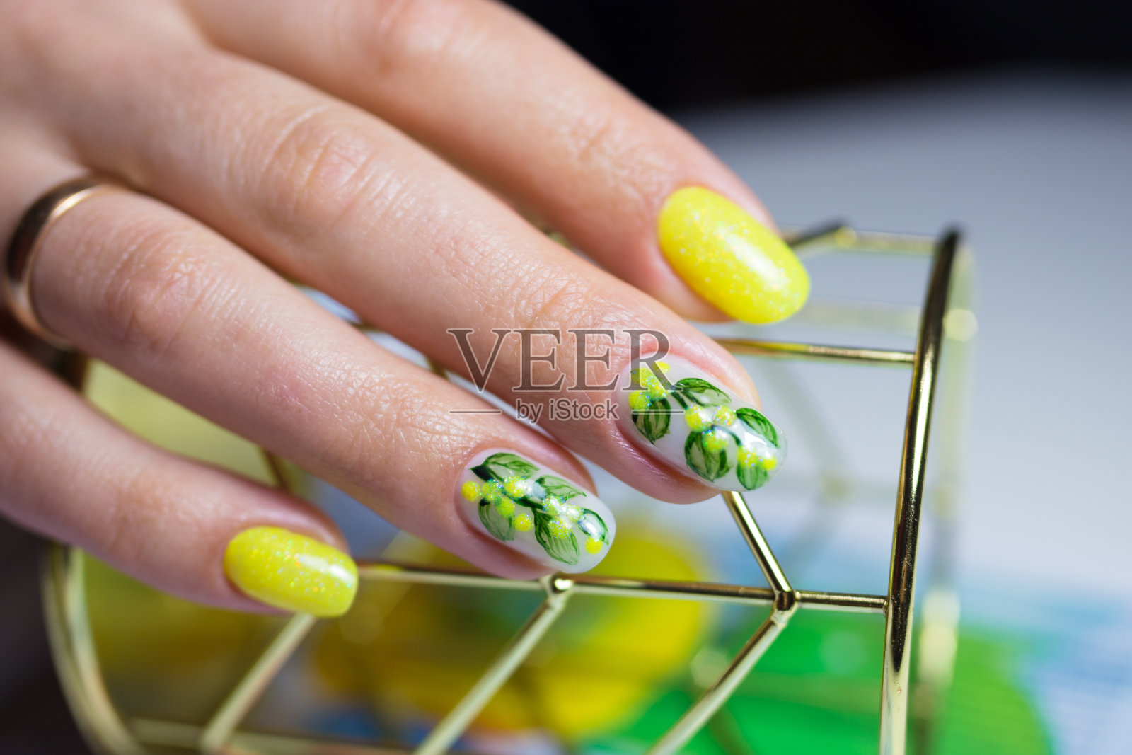 美丽的女性指甲与黄色和绿色美甲。用植物和花卉来设计照片摄影图片